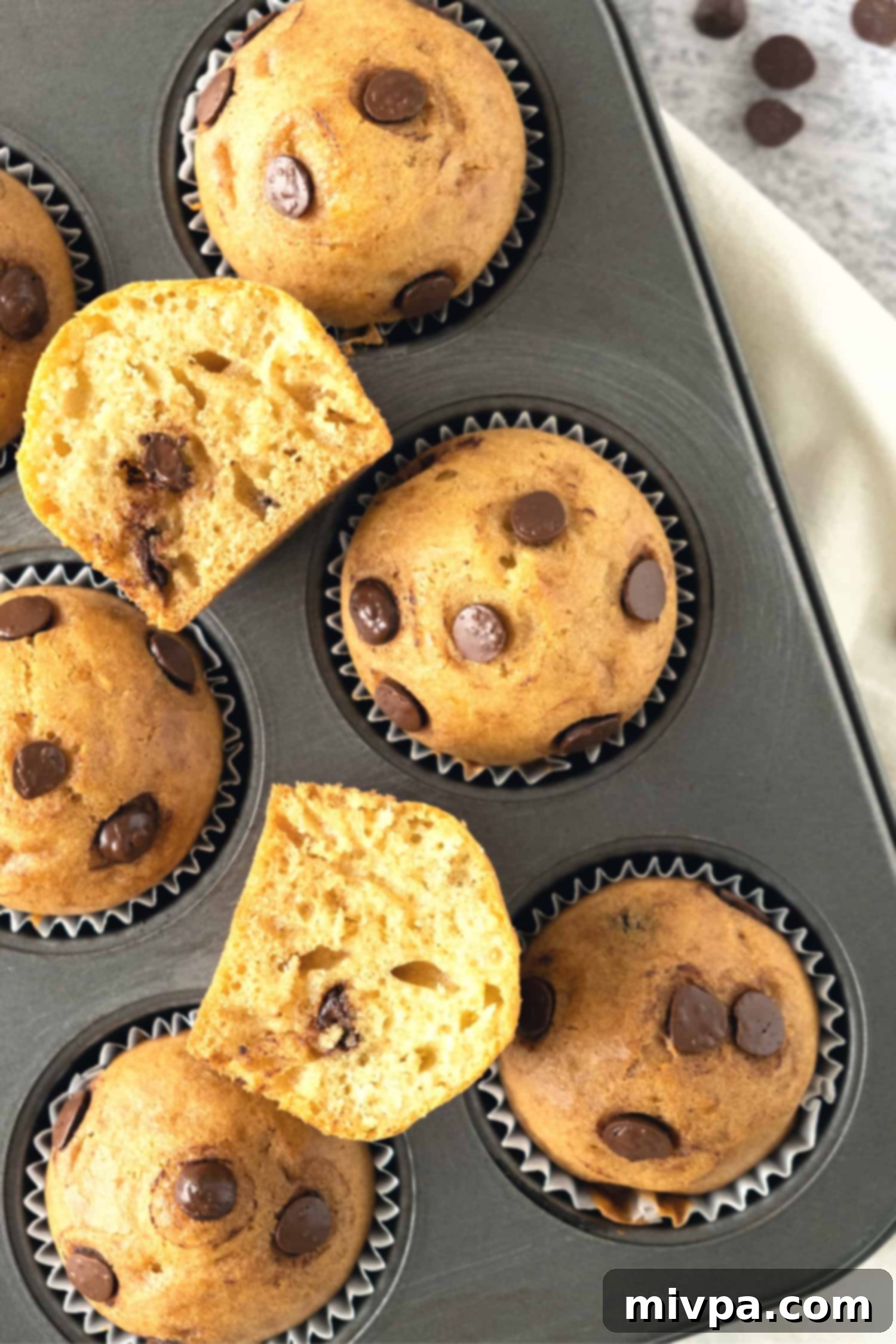 Gluten Free Dairy Free Choc Chip Muffins A muffin pan filled with a freshly baked batch of golden-brown chocolate chip muffins, just out of the oven.