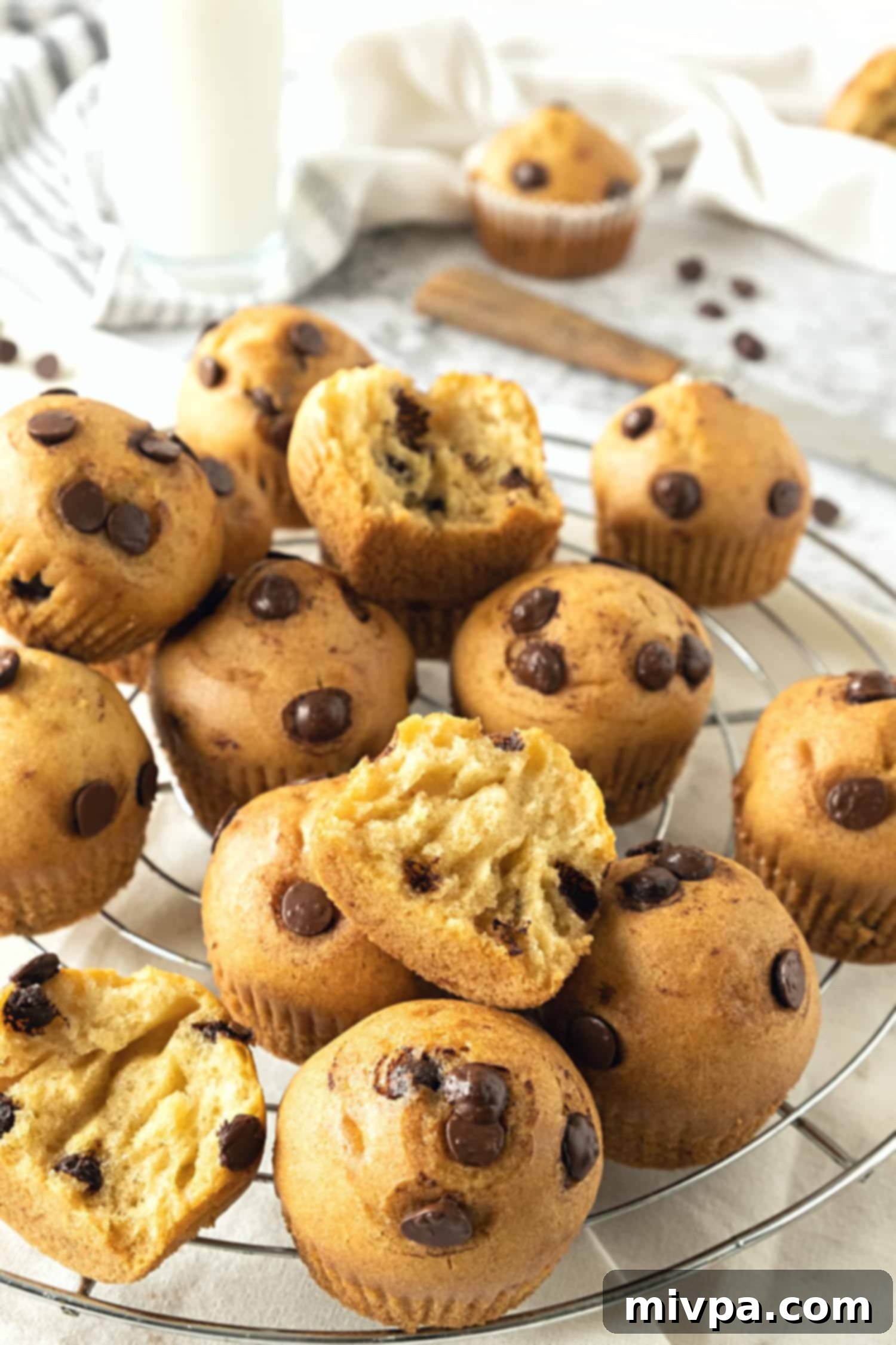 Gluten-Free Chocolate Chip Muffins (Dairy-Free) A collection of freshly baked chocolate chip muffins cooling on a wire rack, steam gently rising.