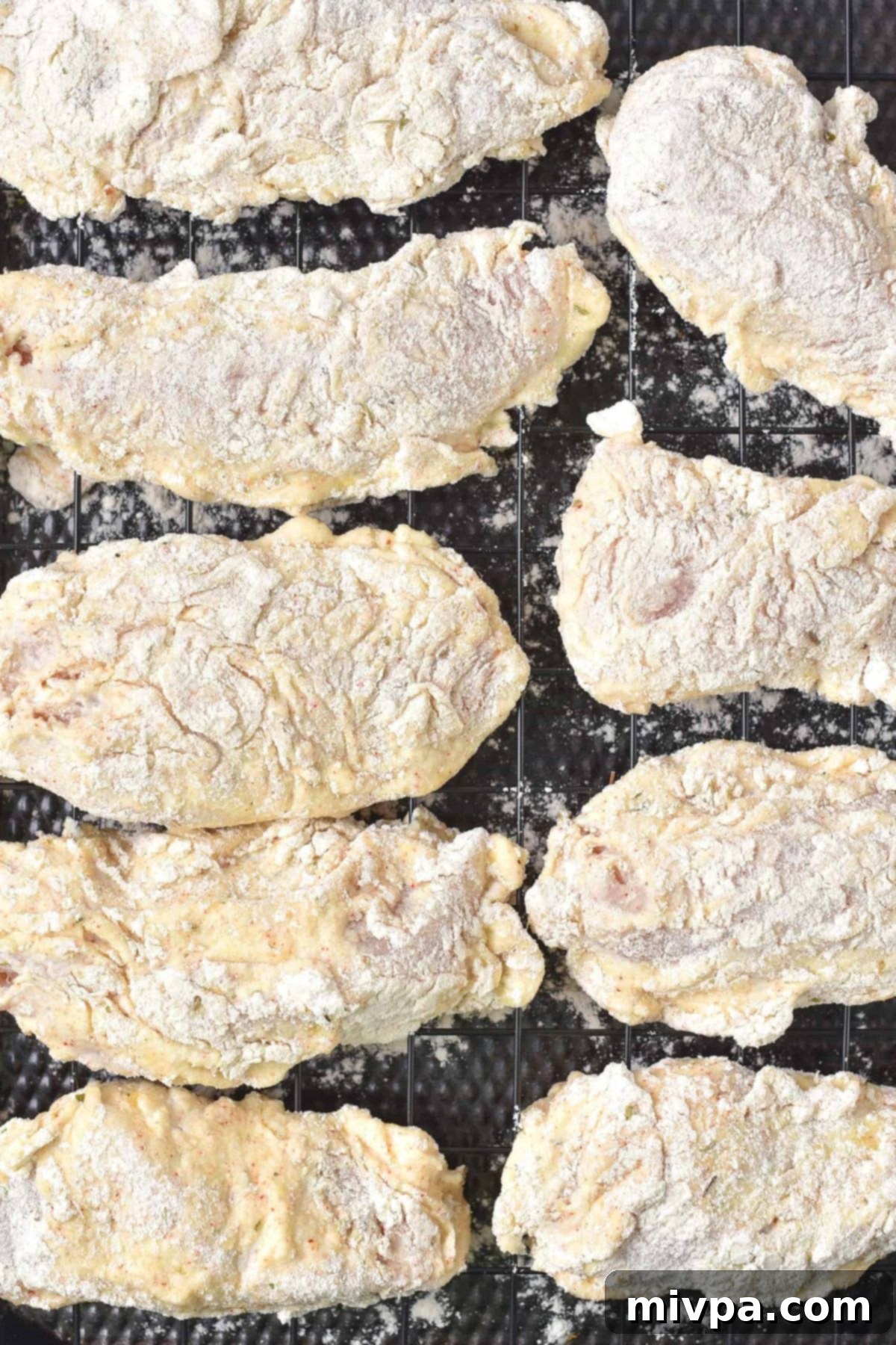 Gluten-Free Fried Chicken Recipe (Dairy-Free) Flour-coated chicken pieces resting on a wire rack over a baking sheet.