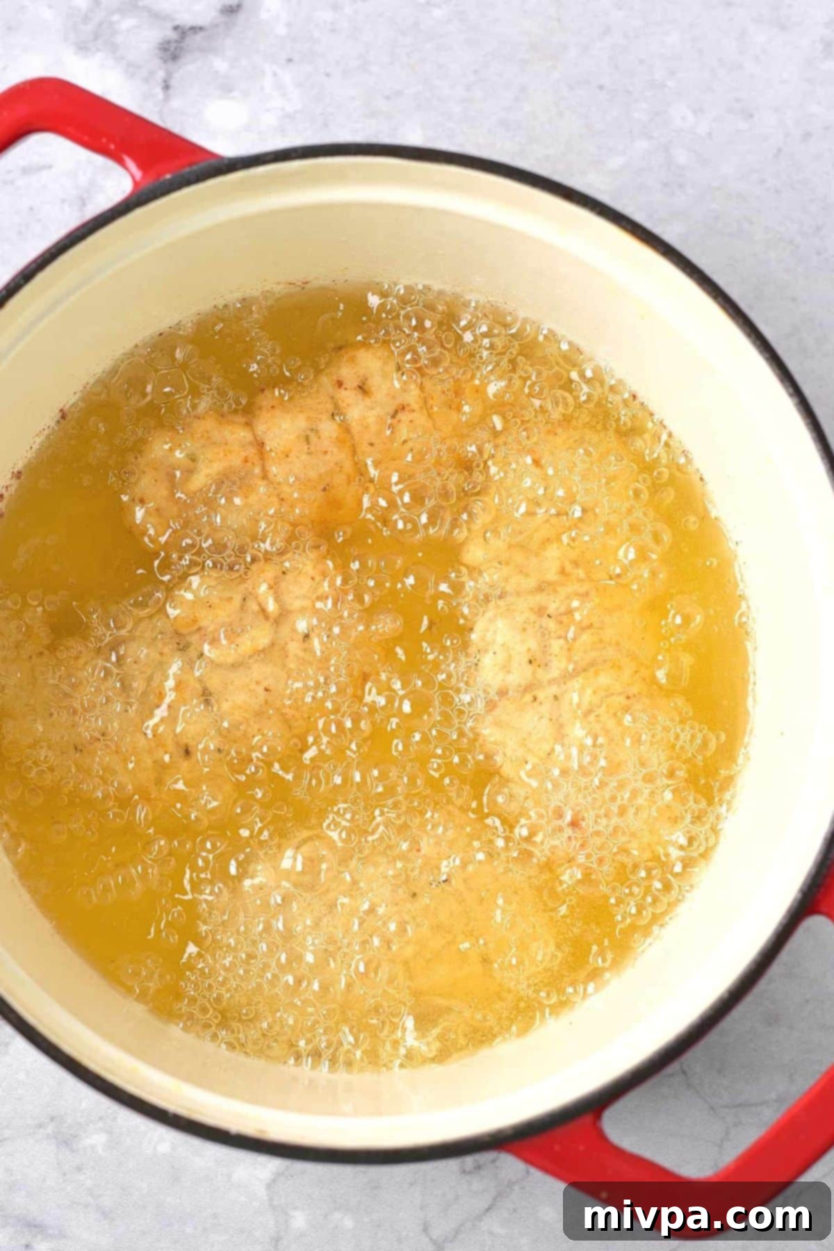 Gluten-Free Fried Chicken (Dairy-Free) Deep frying chicken pieces in a large pot of hot oil, creating a golden, crispy crust.