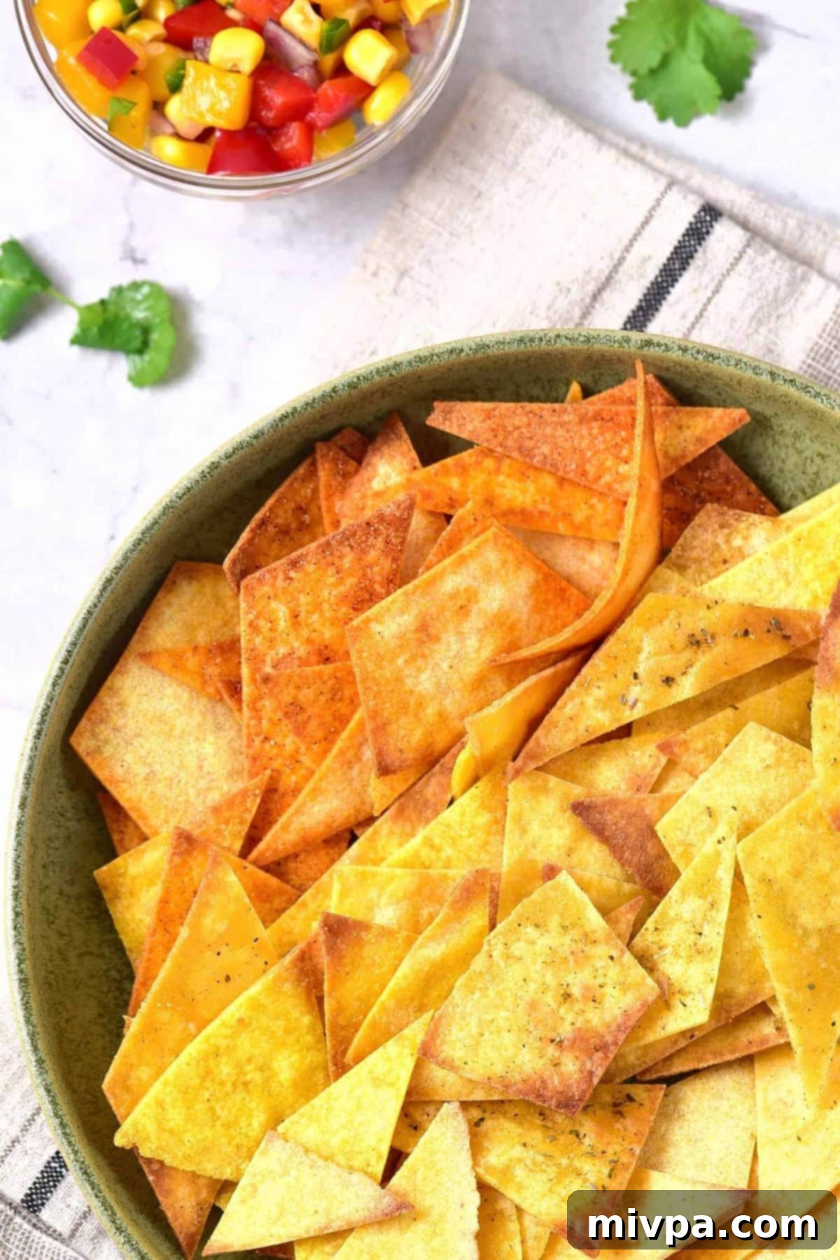 Top down view of corn tortilla chips in a green bowl.
