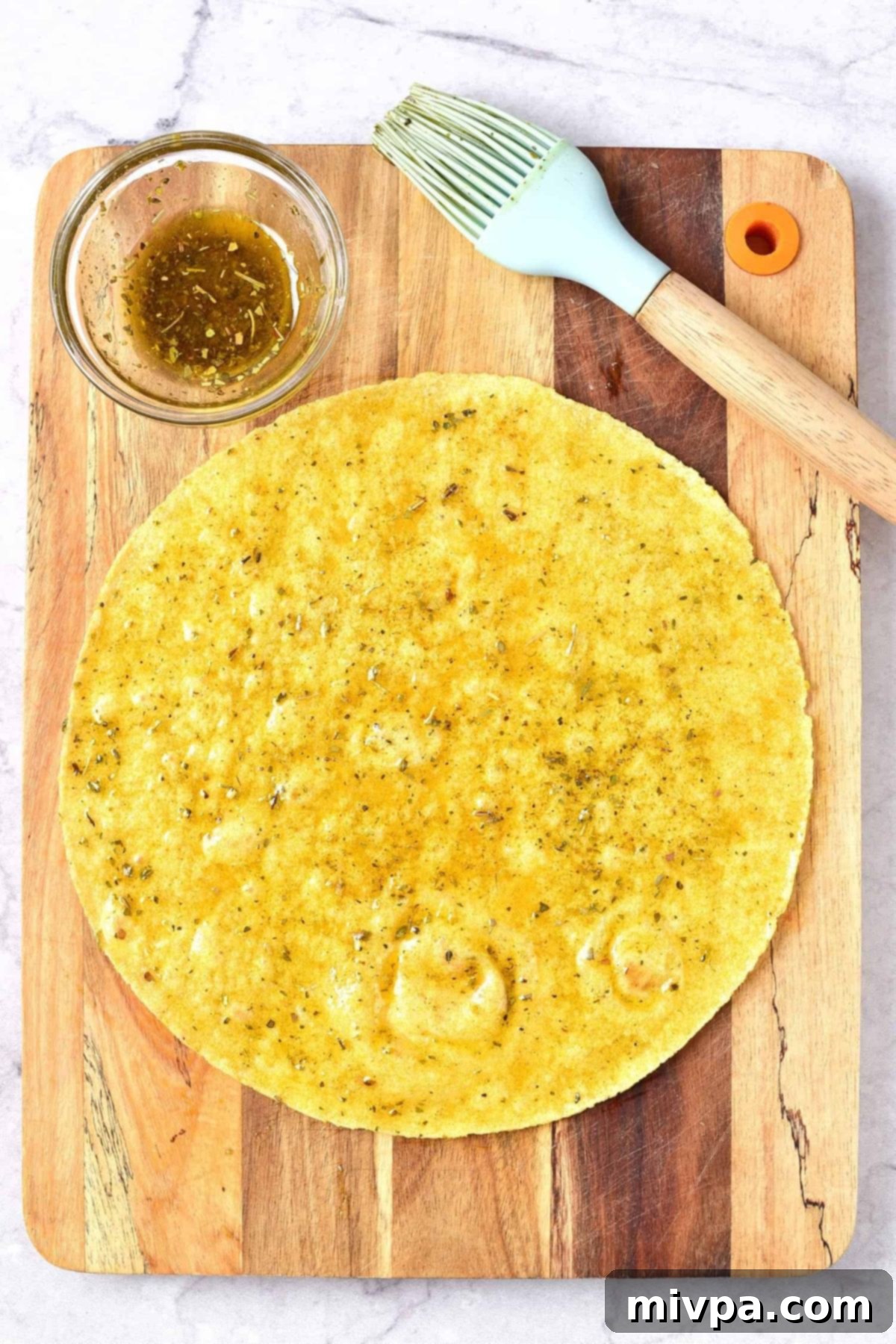 Corn tortilla and brush on wooden board.