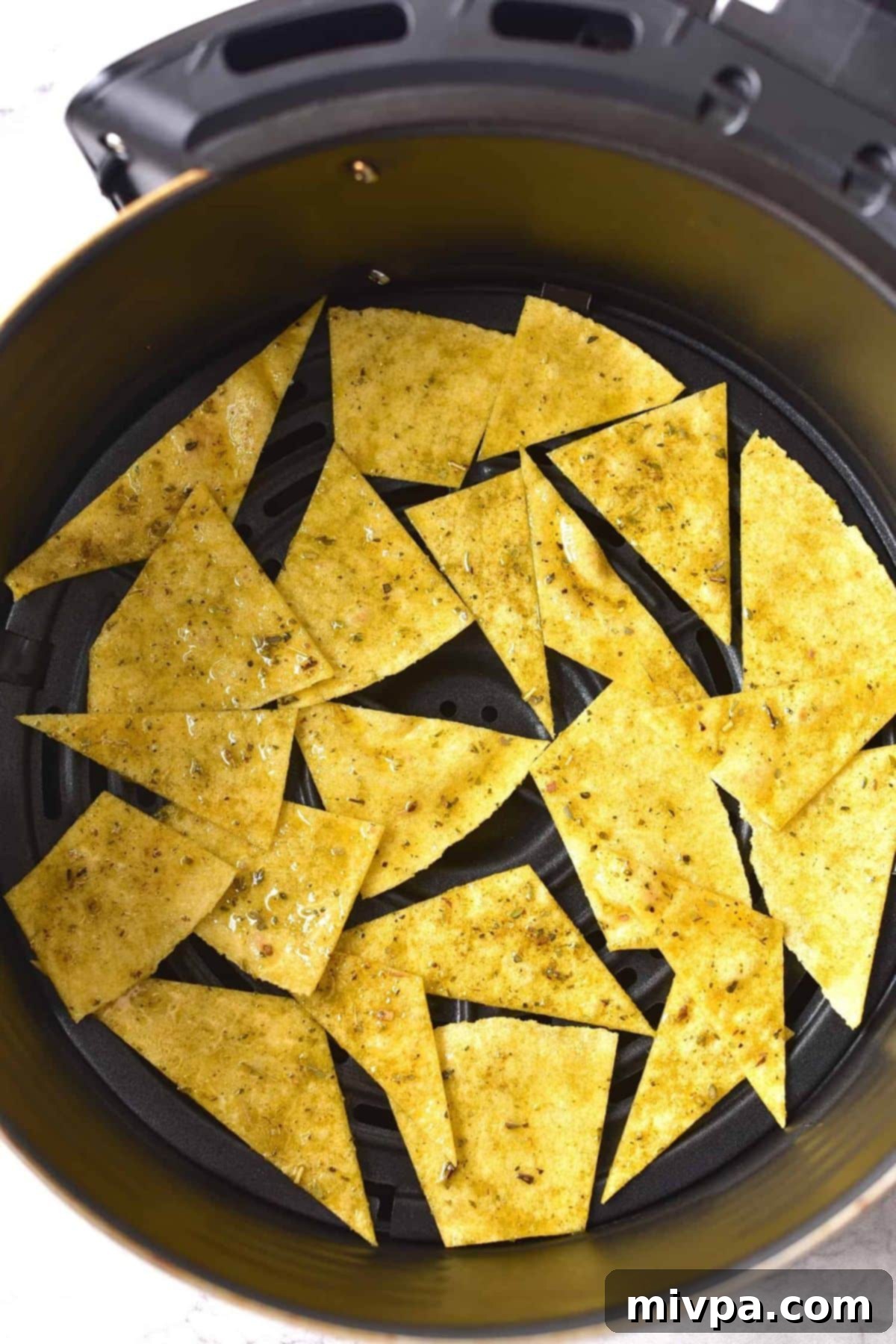 Pieces of corn tortilla in air fryer basket.