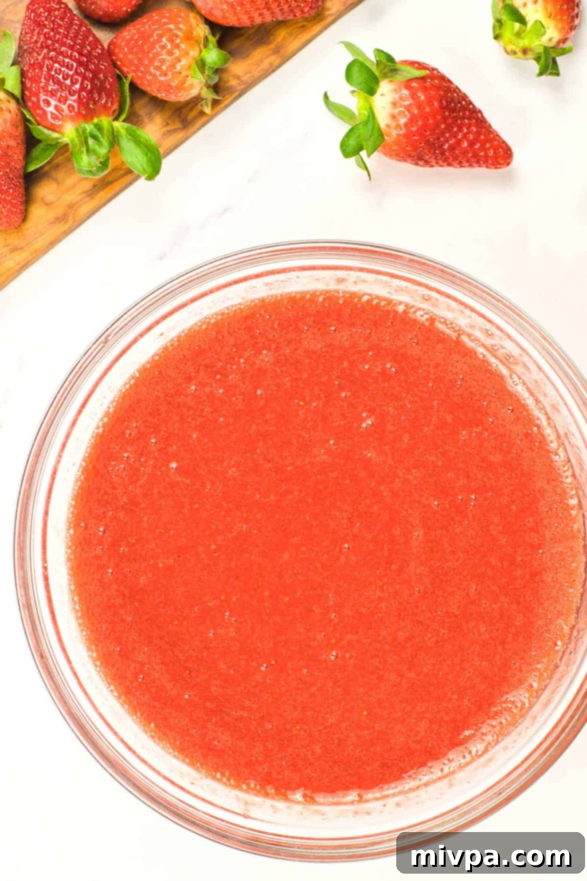 Strawberry Panna Cotta (Gluten-Free, Vegan) A bowl of strawberry sauce surrounded by fresh strawberries.