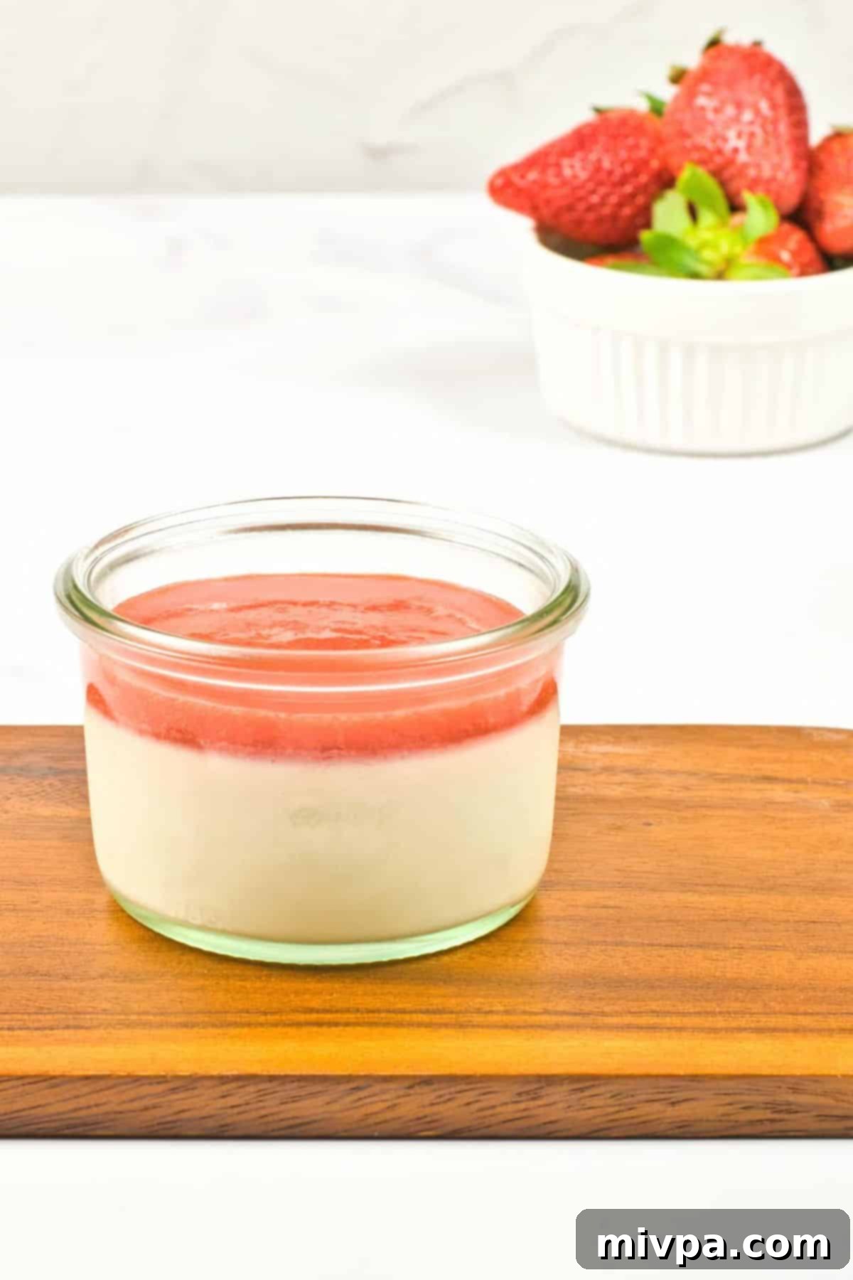 Creamy Coconut Milk Panna Cotta (Gluten-Free, Vegan) A jar of strawberry panna cotta on wooden board.