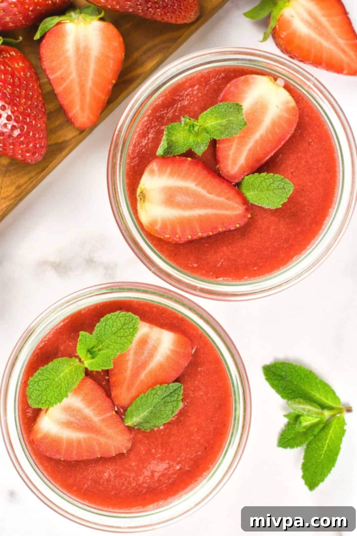 Gluten Free Panna Cotta (Gluten-Free, Vegan) Top down view of strawberry sauce in bowls topped with sliced strawberries.