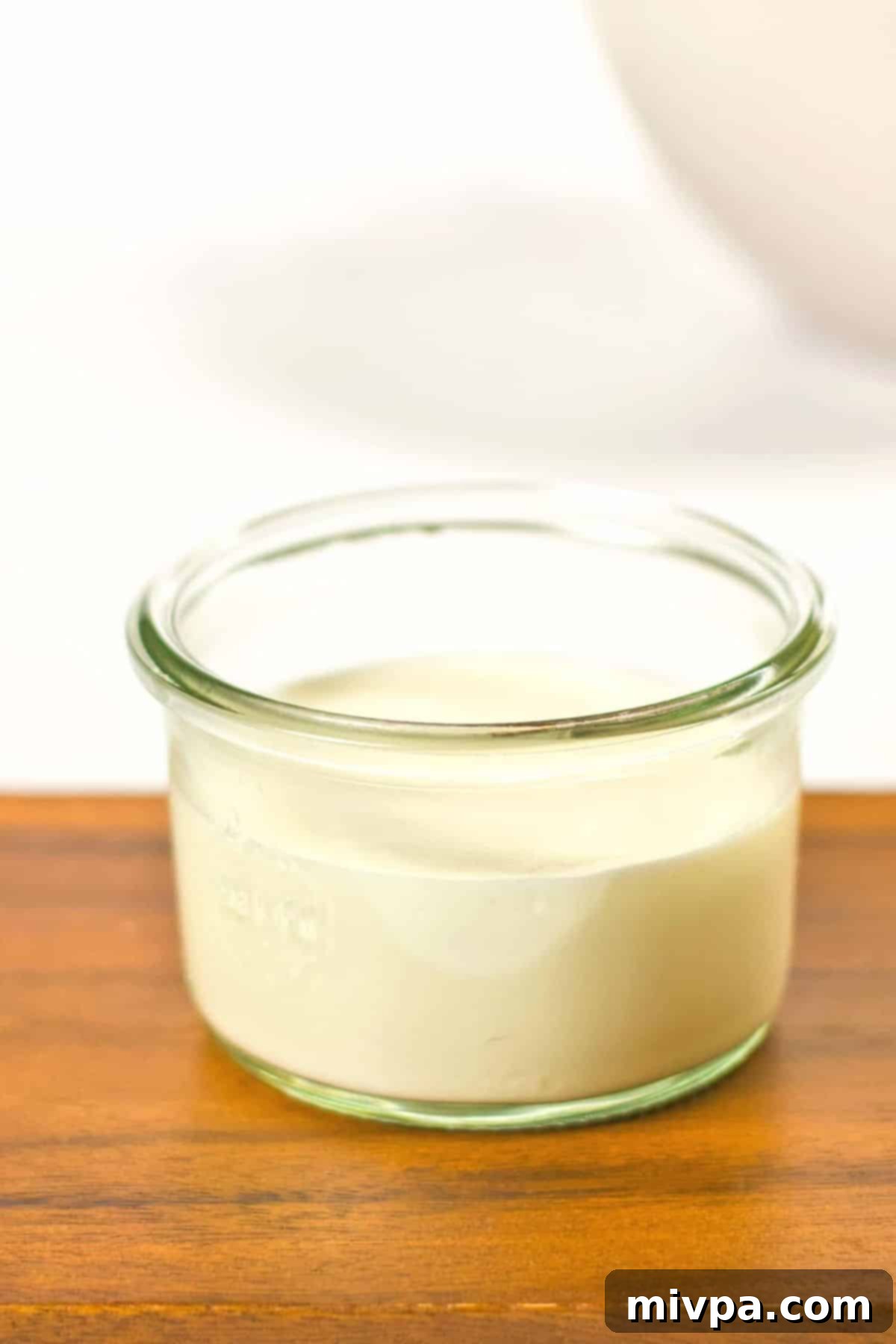 Dairy-Free Panna Cotta (Gluten-Free, Vegan) A glass jar of dairy-free panna cotta on wooden board.