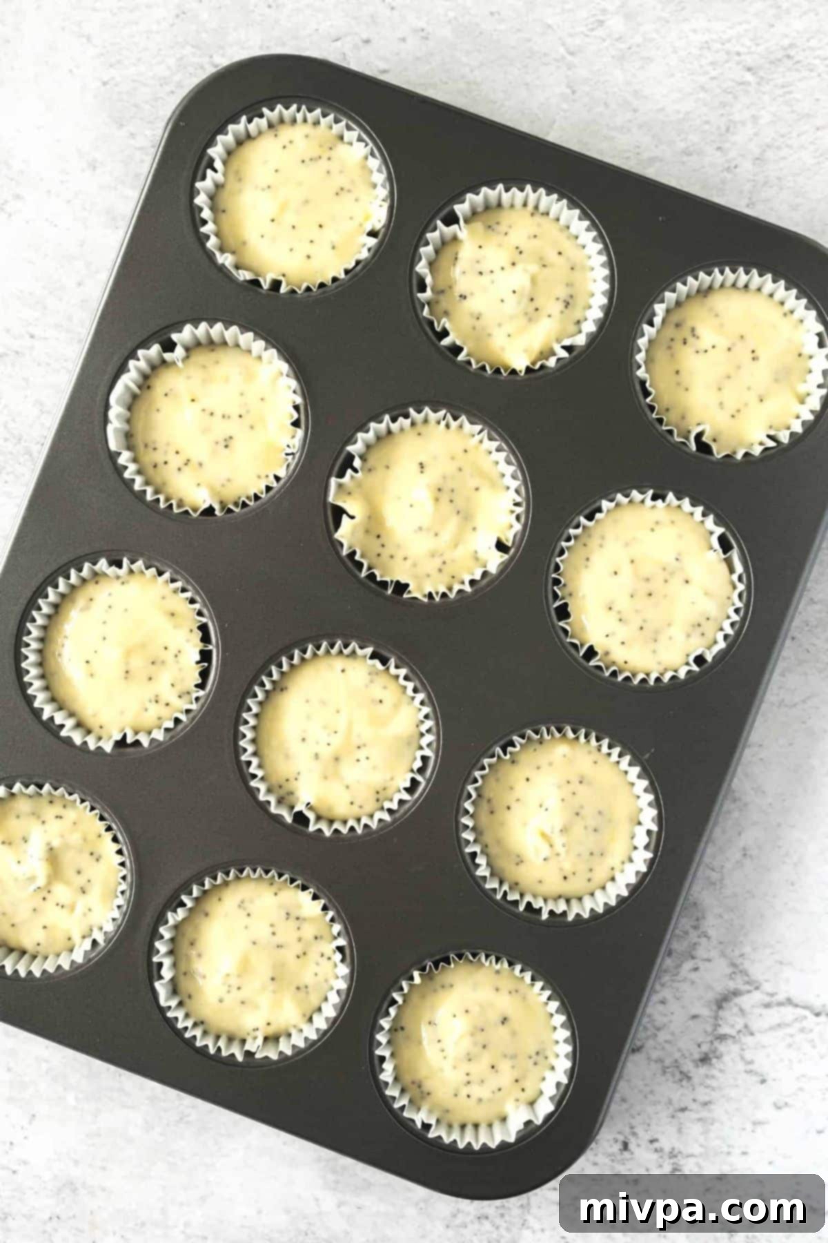 Gluten-Free Lemon Poppyseed Muffins (Dairy-Free) Muffin batter neatly scooped into each of the 12 muffin cups in a prepared muffin pan, ready for baking.