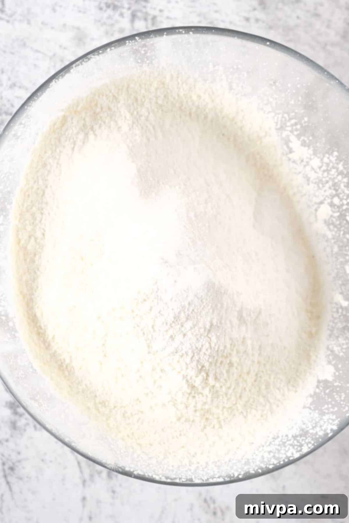 Gluten-Free Poppy Seed Muffins (Dairy-Free) A glass bowl filled with the sifted dry ingredients: gluten-free flour, salt, baking powder, xanthan gum, and poppy seeds.