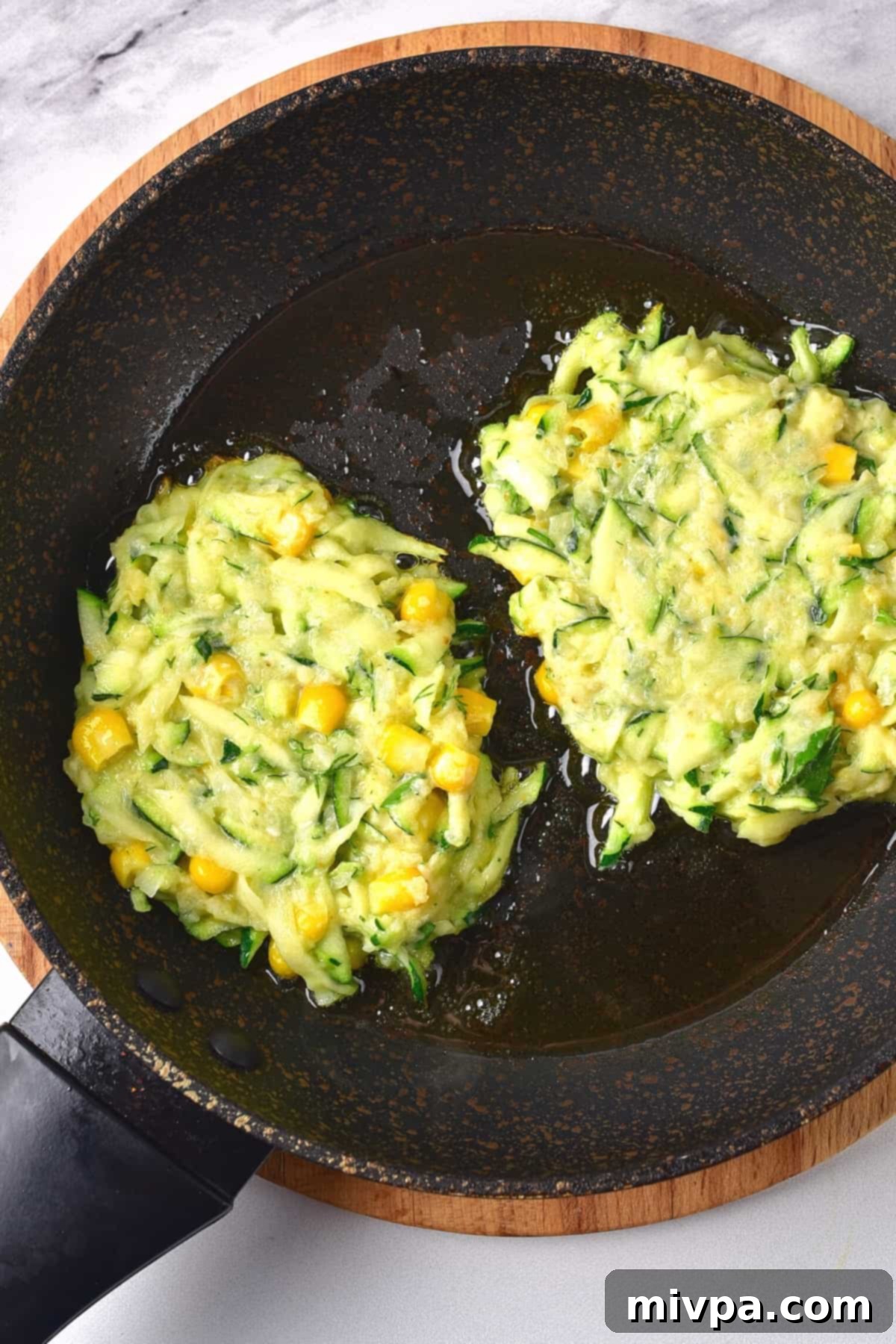Frying zucchini fritters in a skillet.