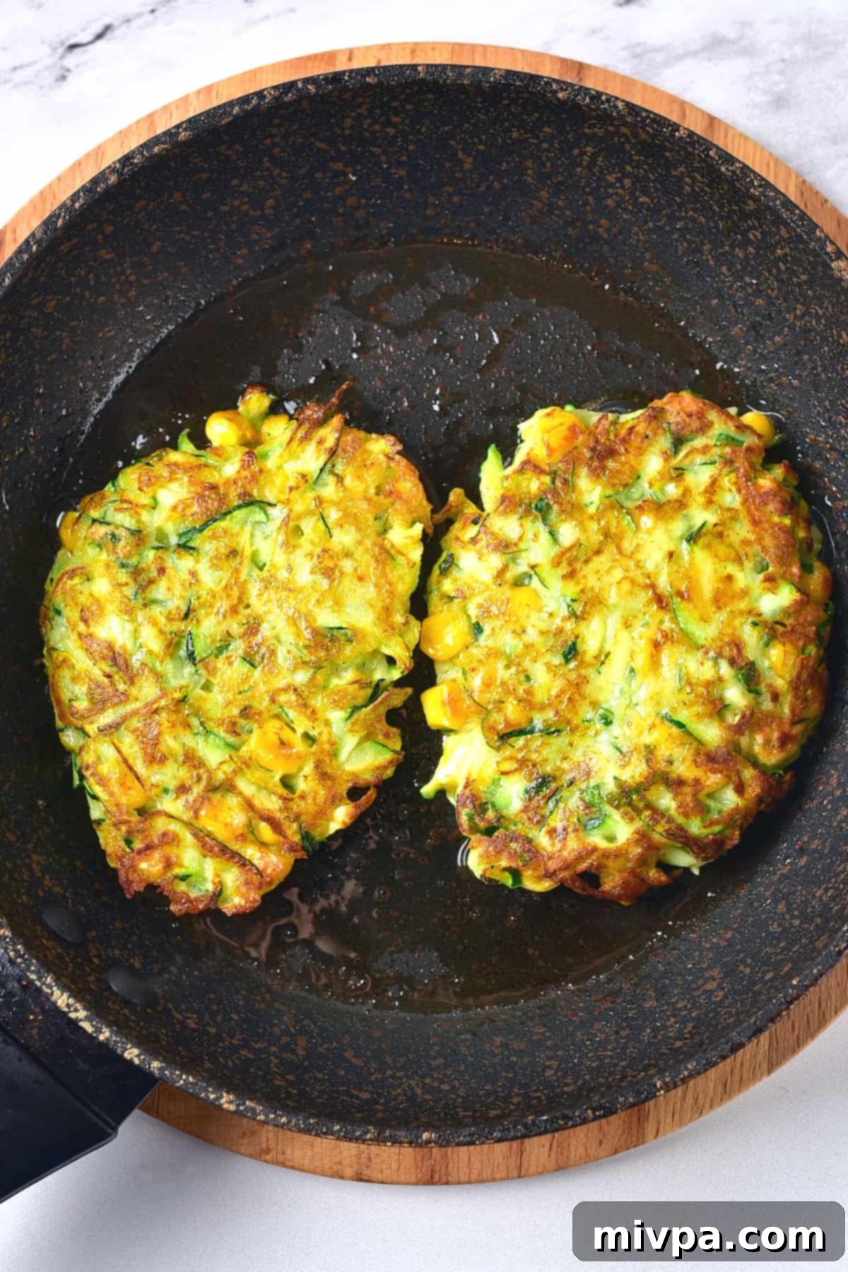 Freshly cooked zucchini and corn fritters in a pan.