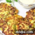 Crispy gluten-free zucchini fritters with corn, served with a dipping sauce.