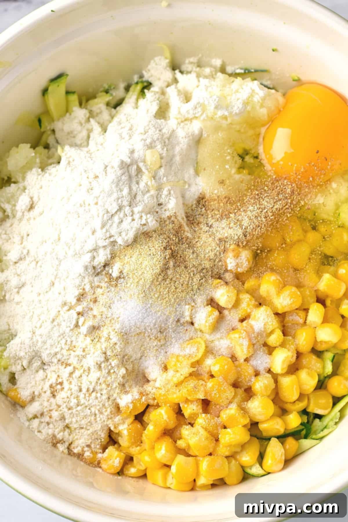 Ingredients for courgetti fritters in a white bowl.