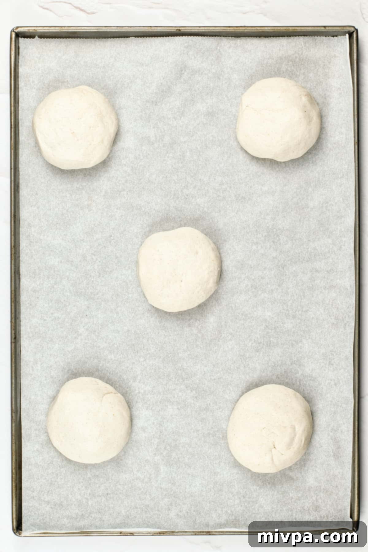 Gluten-Free Pita Bread Recipe (Dairy-Free, Vegan) Precisely divided balls of gluten-free pita dough, arranged on a parchment-lined sheet.