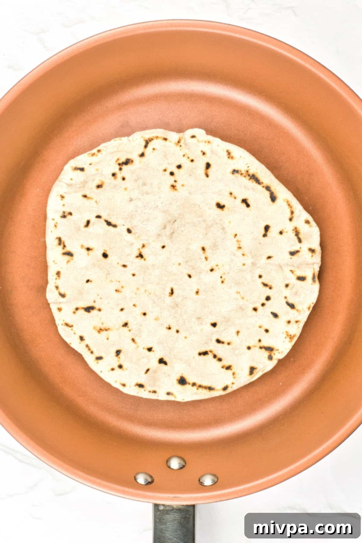 Gluten-Free Dairy-Free Pita Bread A freshly cooked gluten-free pita bread, perfectly puffed and golden brown, in a skillet.