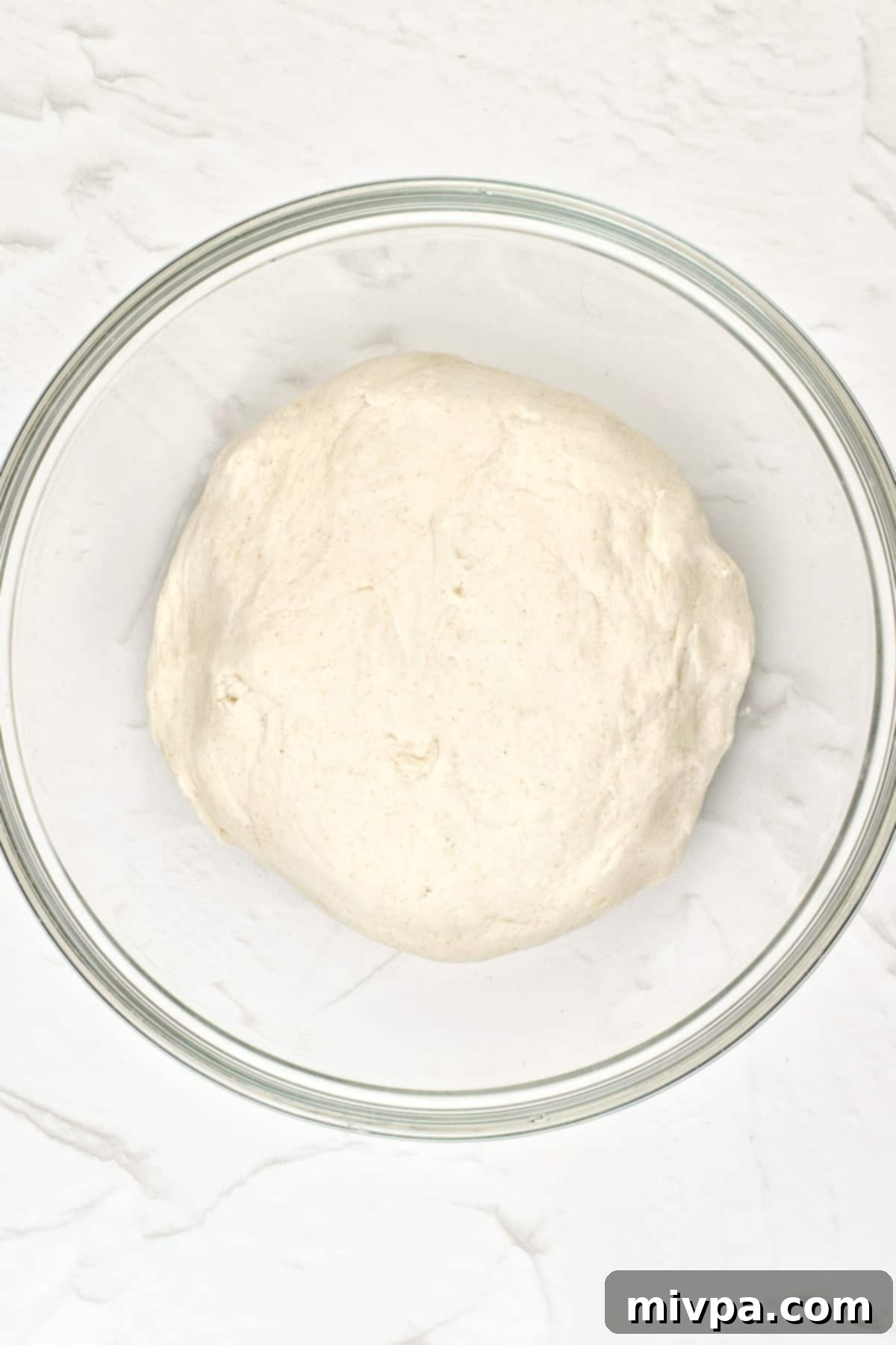 Dairy-Free Pita Bread (Gluten-Free, Vegan) A smooth, elastic gluten-free pita dough resting in a glass bowl.