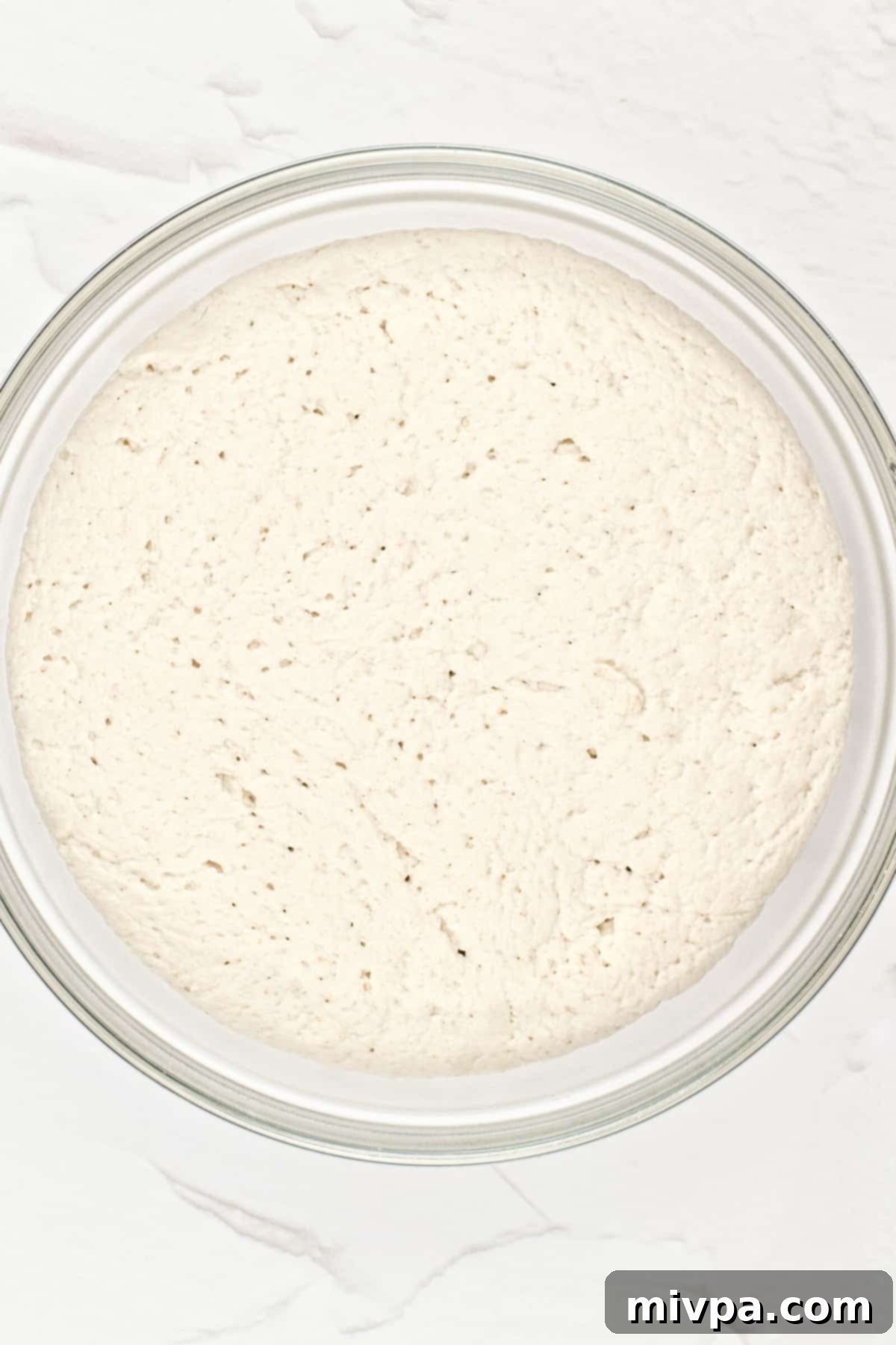 Gluten-Free Pita Recipe Leavened pita bread dough in a bowl, visibly expanded after rising.