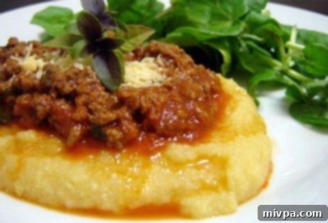 Traditional Polenta Serving A bowl of creamy, boiled polenta topped generously with a rich, red tomato sauce, illustrating a typical Italian serving style.