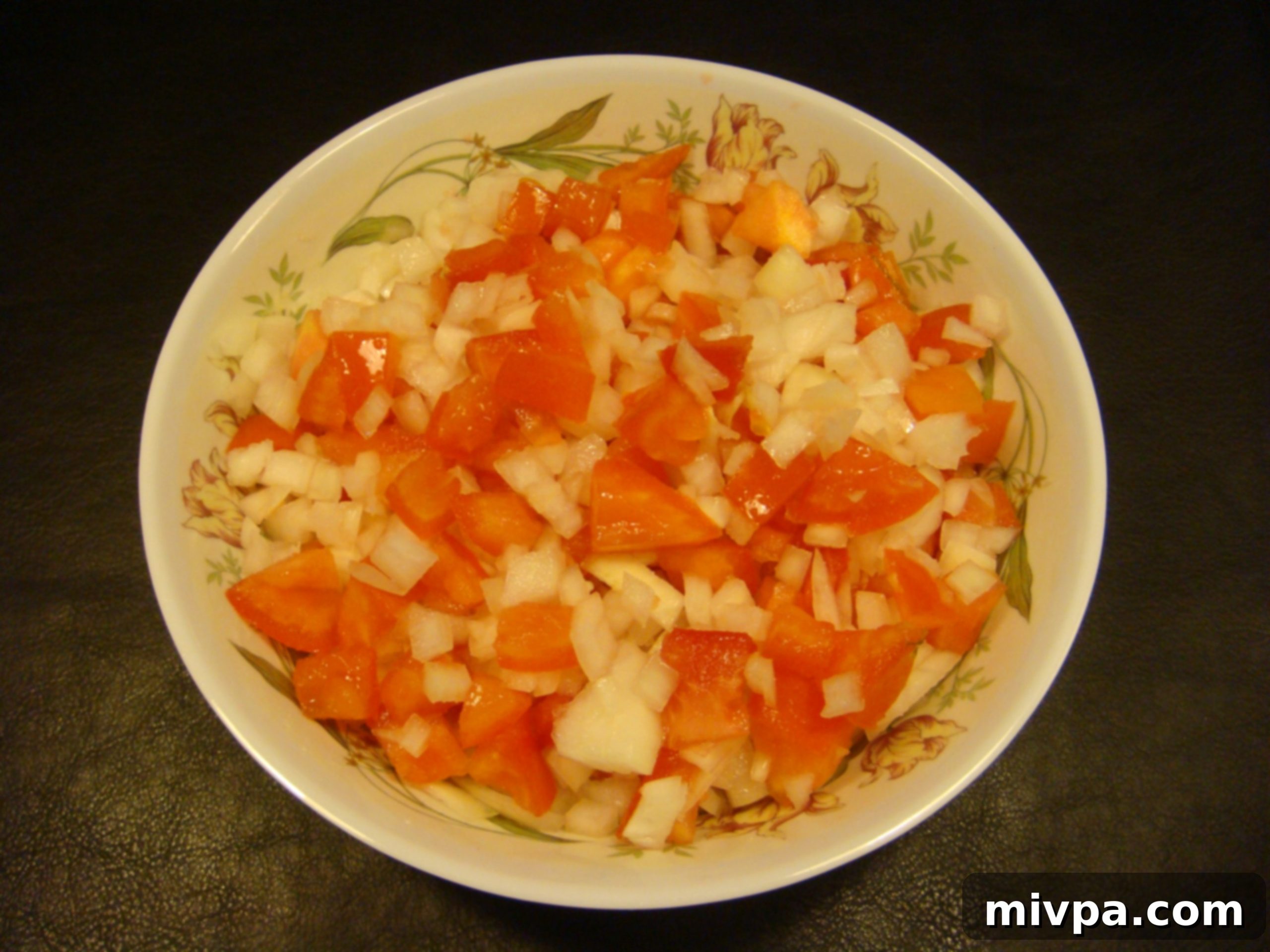 Tomato Onion Topping Mixture A bowl containing a vibrant mixture of chopped tomatoes and onions, glistening with olive oil and seasoned with salt, ready for the bruschetta.