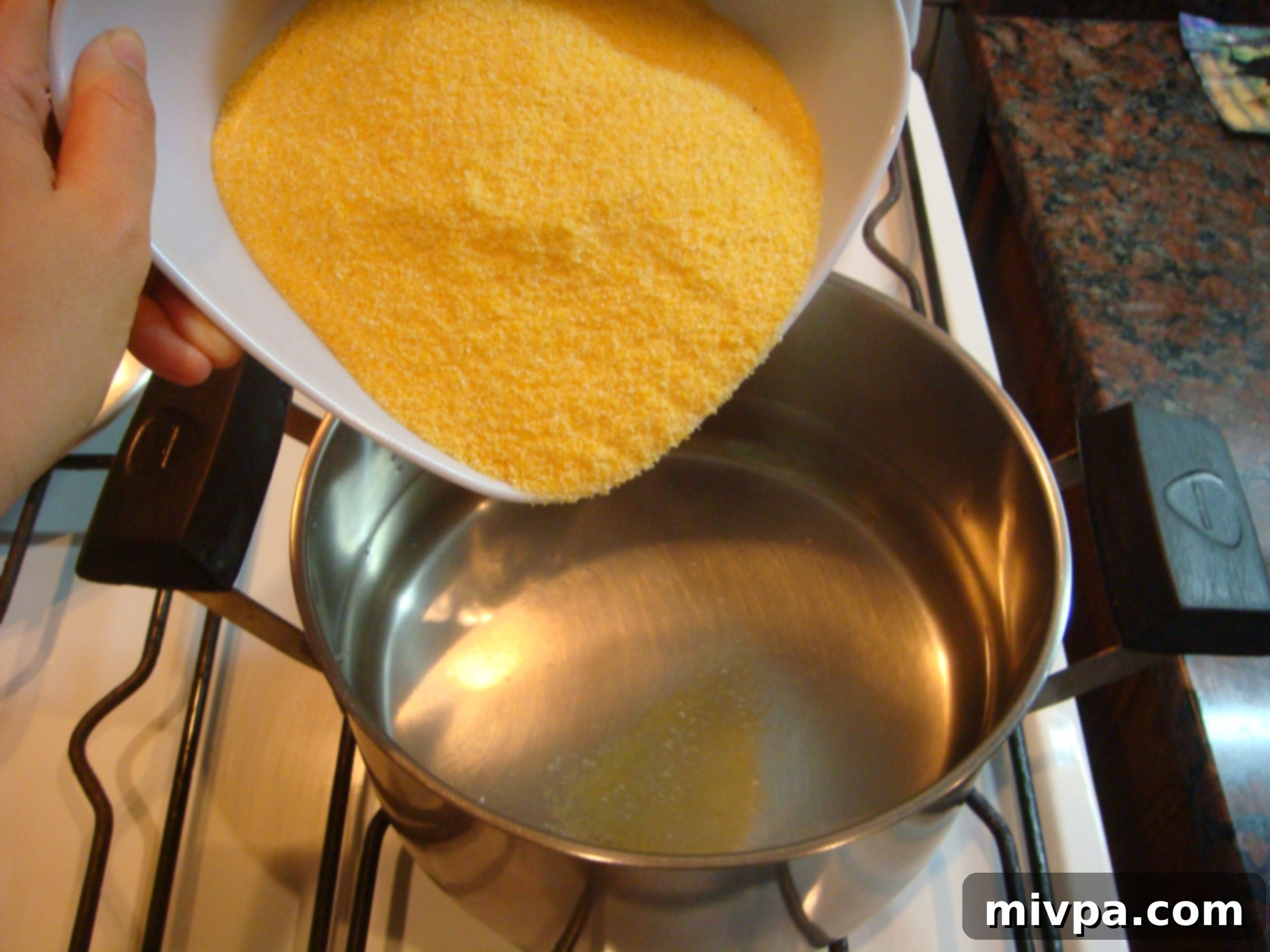 Adding Polenta to Water Instant polenta mix being poured steadily into a pot of hot water, creating a 'rainfall' effect as it disperses.