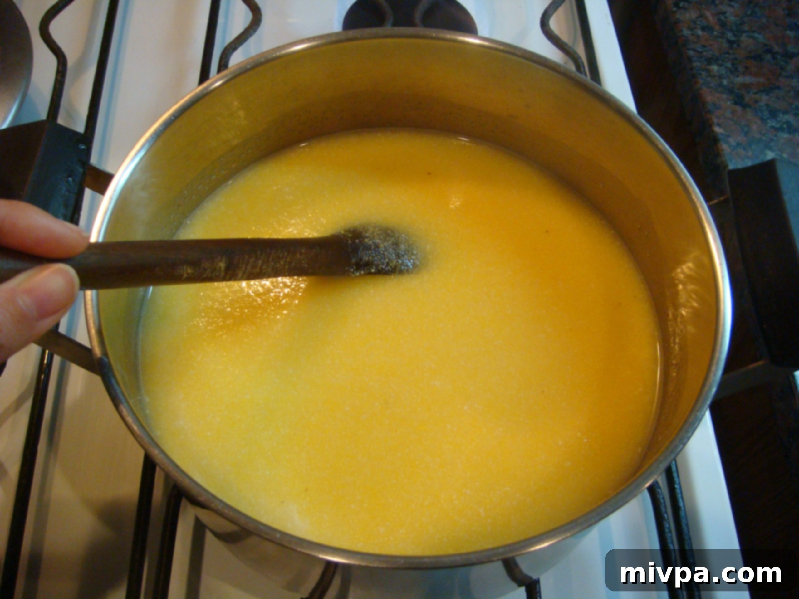 Stirring Polenta Constantly A hand stirring the polenta mixture vigorously in a pot, ensuring even cooking and preventing lumps.