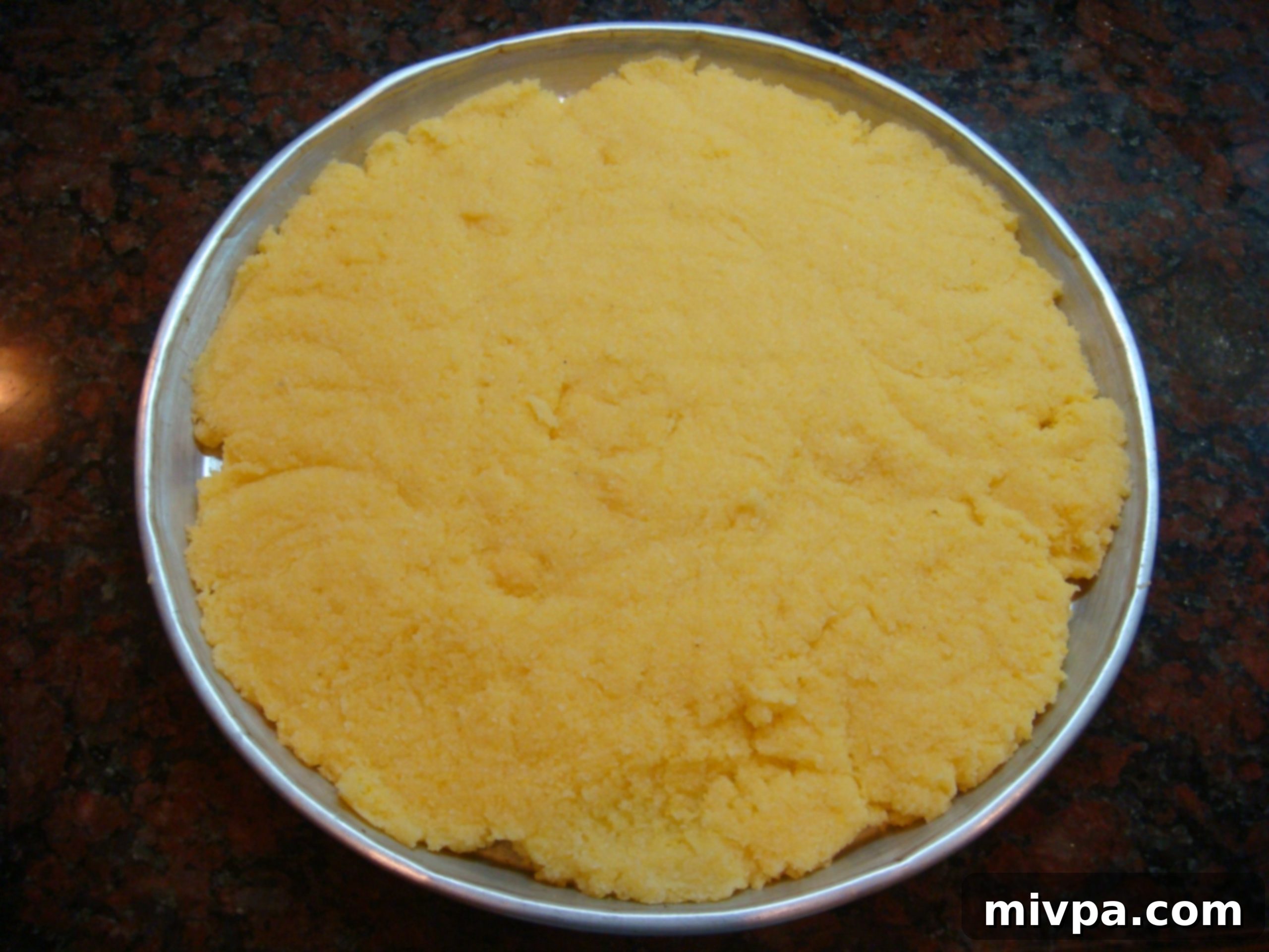 Spreading Polenta in Tray Cooked polenta being spread evenly onto a flat baking tray with a spatula, to a thickness of about 1-1.5cm.