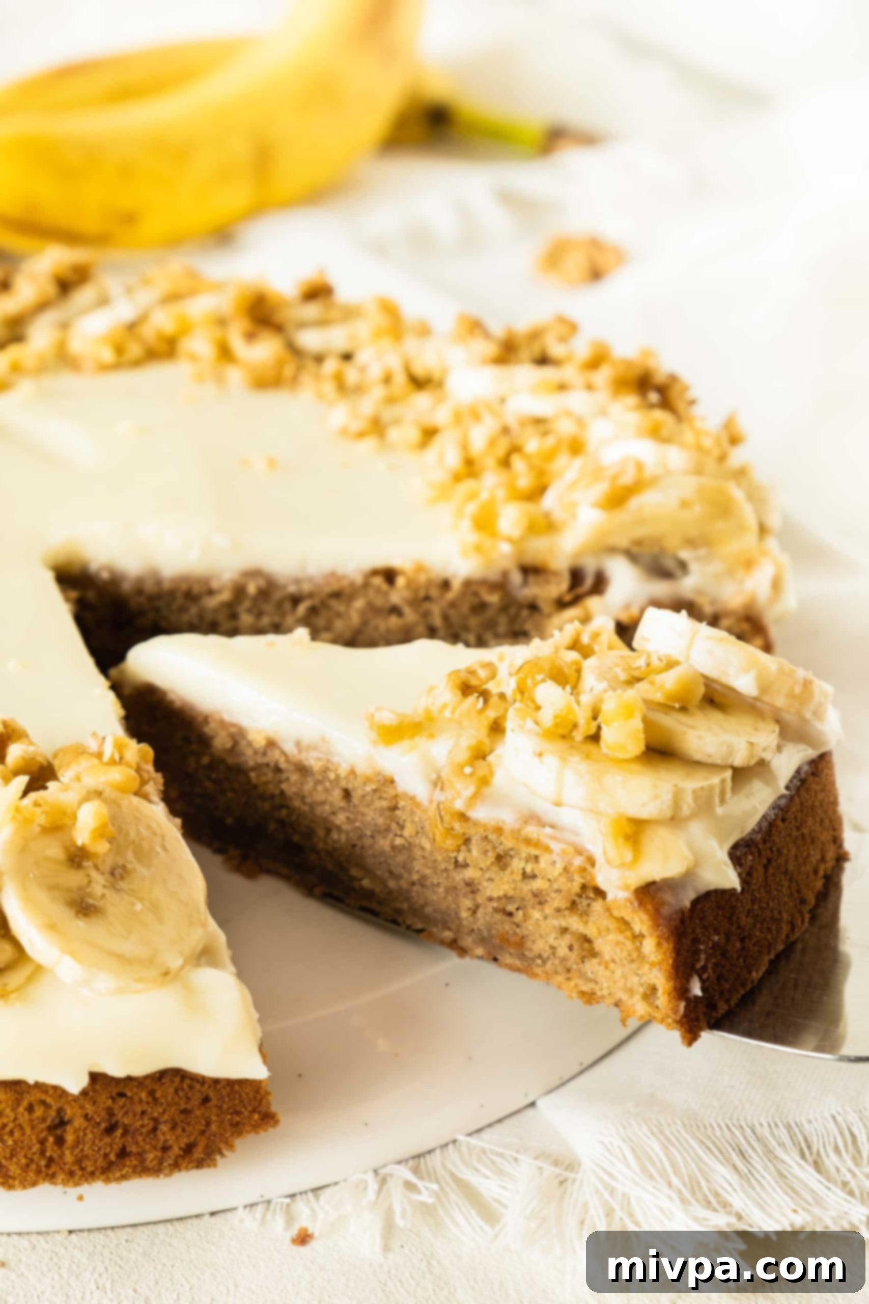 Easy Gluten-Free Banana Cake (Dairy-Free) Reaching for a slice of gluten-free banana cake on cake stand.