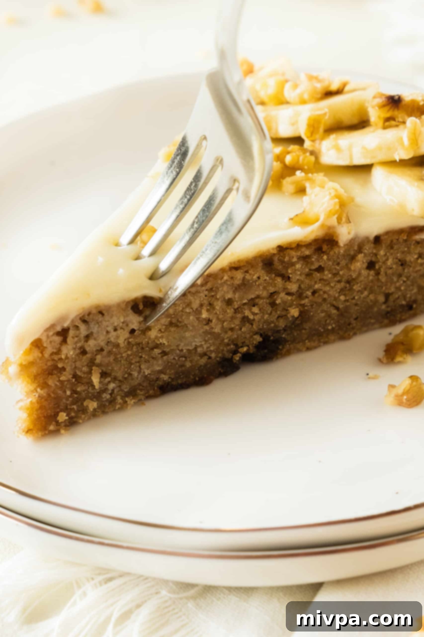 Easy Gluten-Free Banana Cake (Dairy-Free) Cutting into a slice of banana cake with cream cheese frosting.