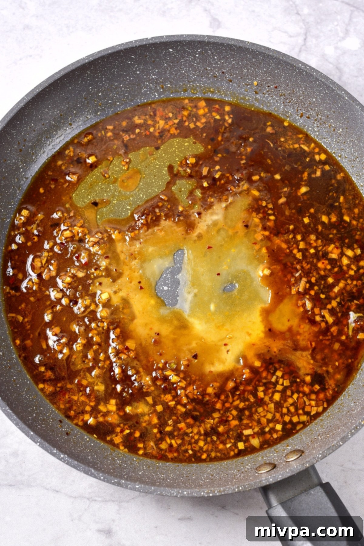 Gluten-Free Orange Chicken Sauce The orange chicken sauce thickening in the skillet after the addition of a cornstarch slurry, becoming glossy and rich.