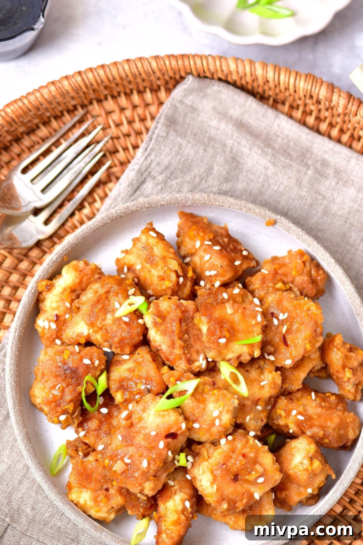 Easy Gluten-Free Orange Chicken Recipe (Dairy-Free) A top-down view of a platter showcasing gluten-free orange chicken, perfectly arranged on a kitchen towel, ready to be served.