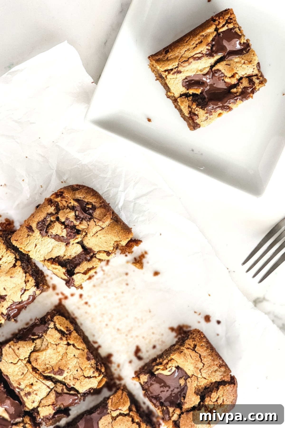 Top down view of neatly arranged peanut butter cookie bars on parchment paper, ready to be served.