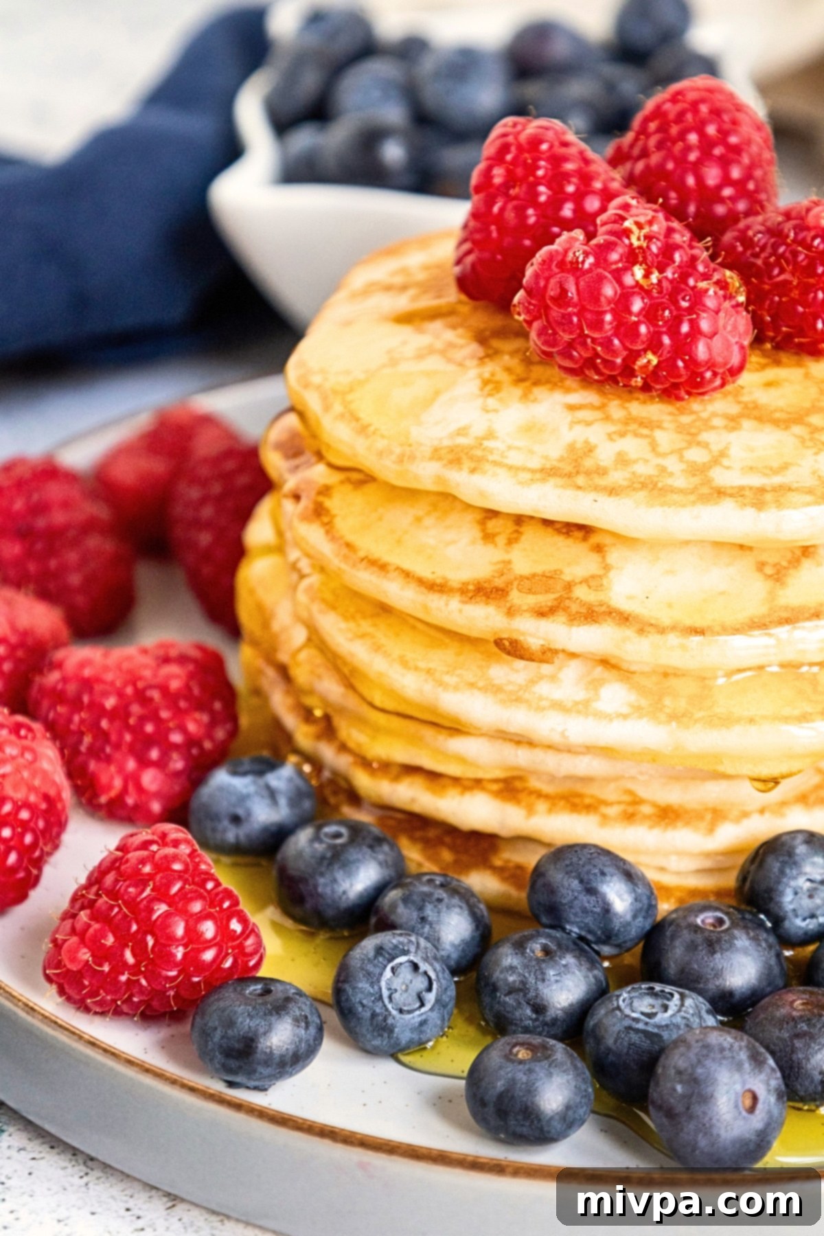 Up close shot of a stack of gluten-free buttermilk pancakes topped with berries.