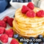 A stack of buttermilk pancakes topped with berries.