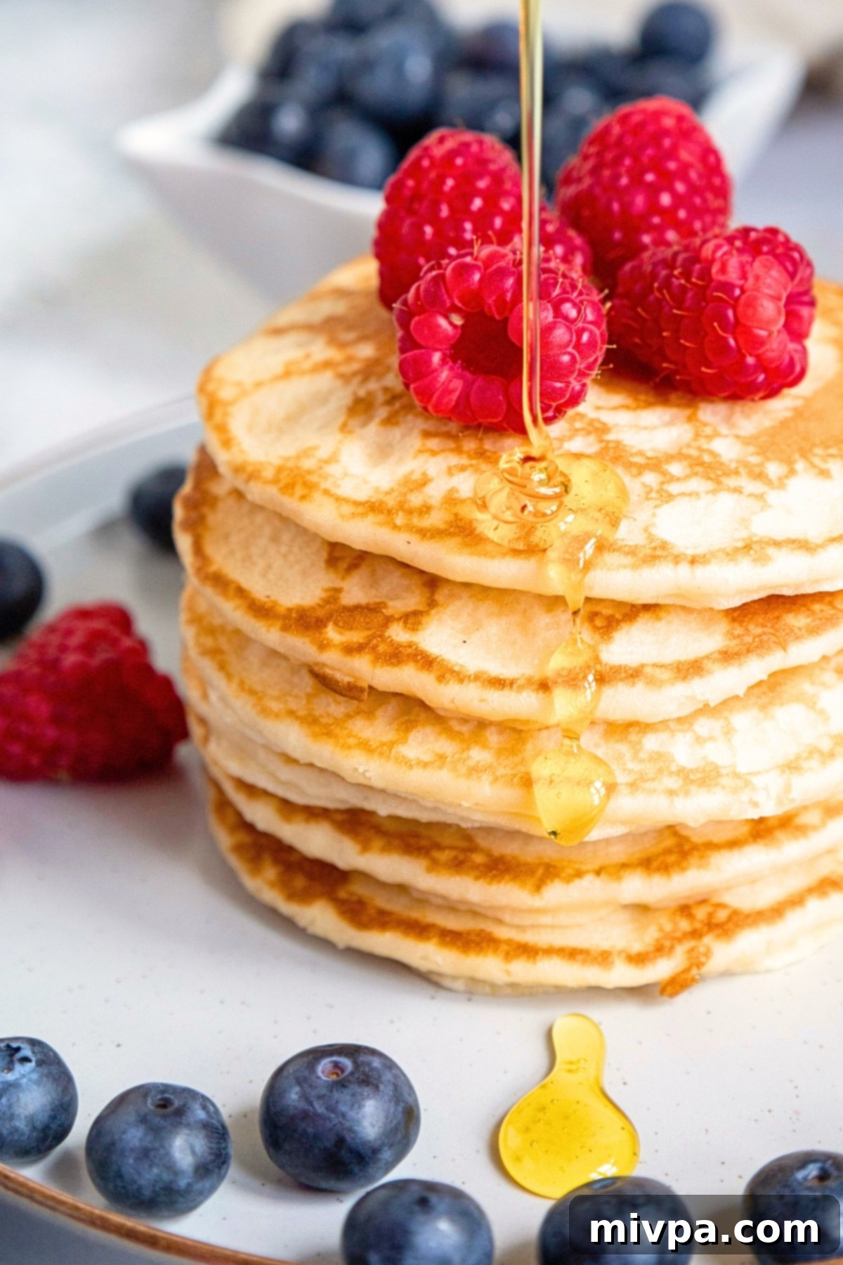 Drizzling maple syrup over a stack of gf buttermilk pancakes.