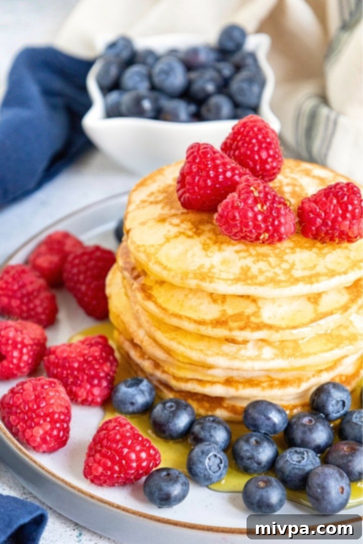 A plate of buttermilk pancakes surrounded by fresh berries.