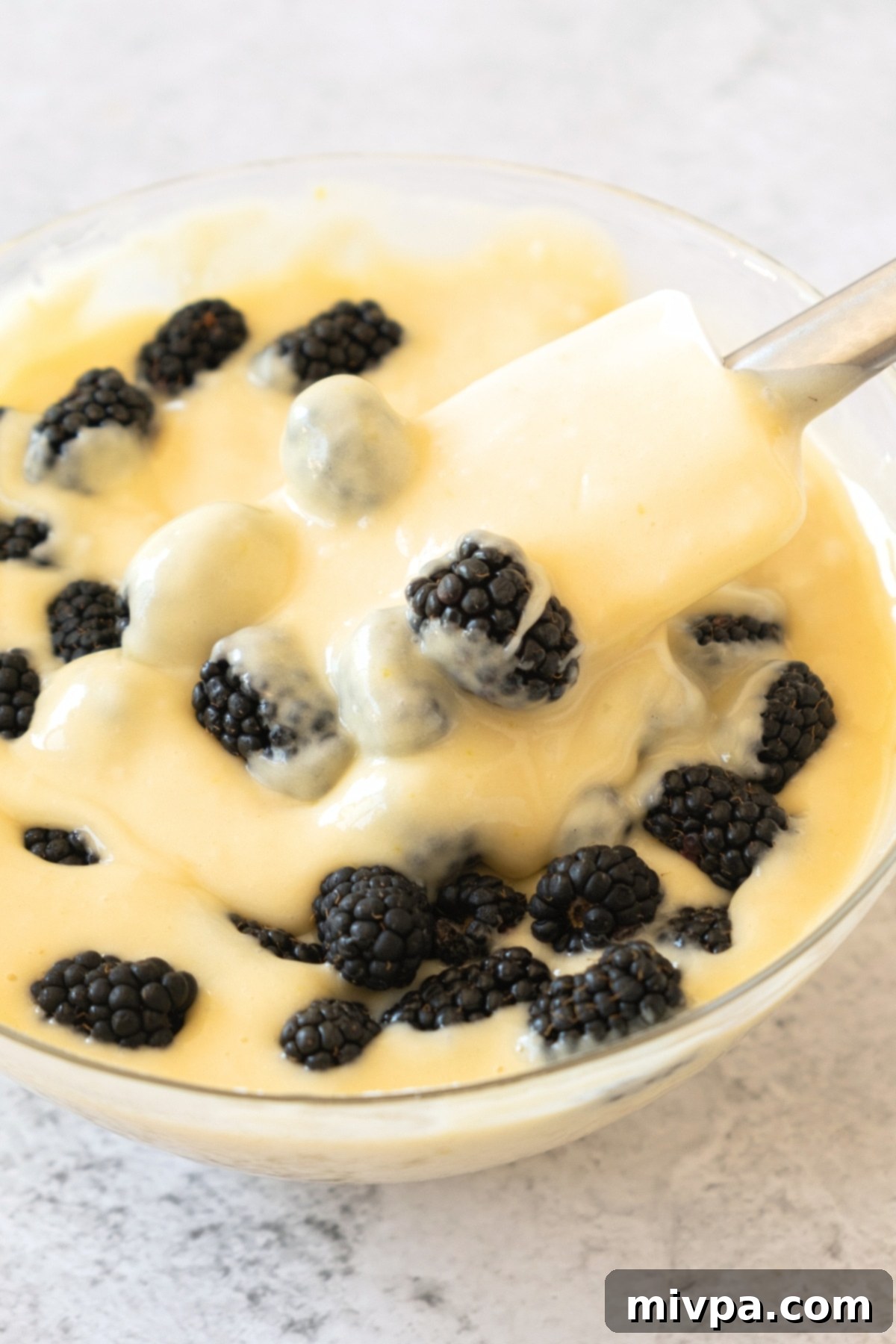 Folding fresh blackberries into muffin batter.