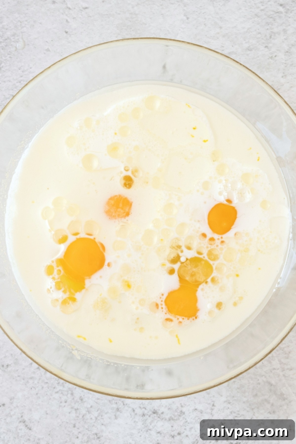 Milk and eggs in glass mixing bowl.