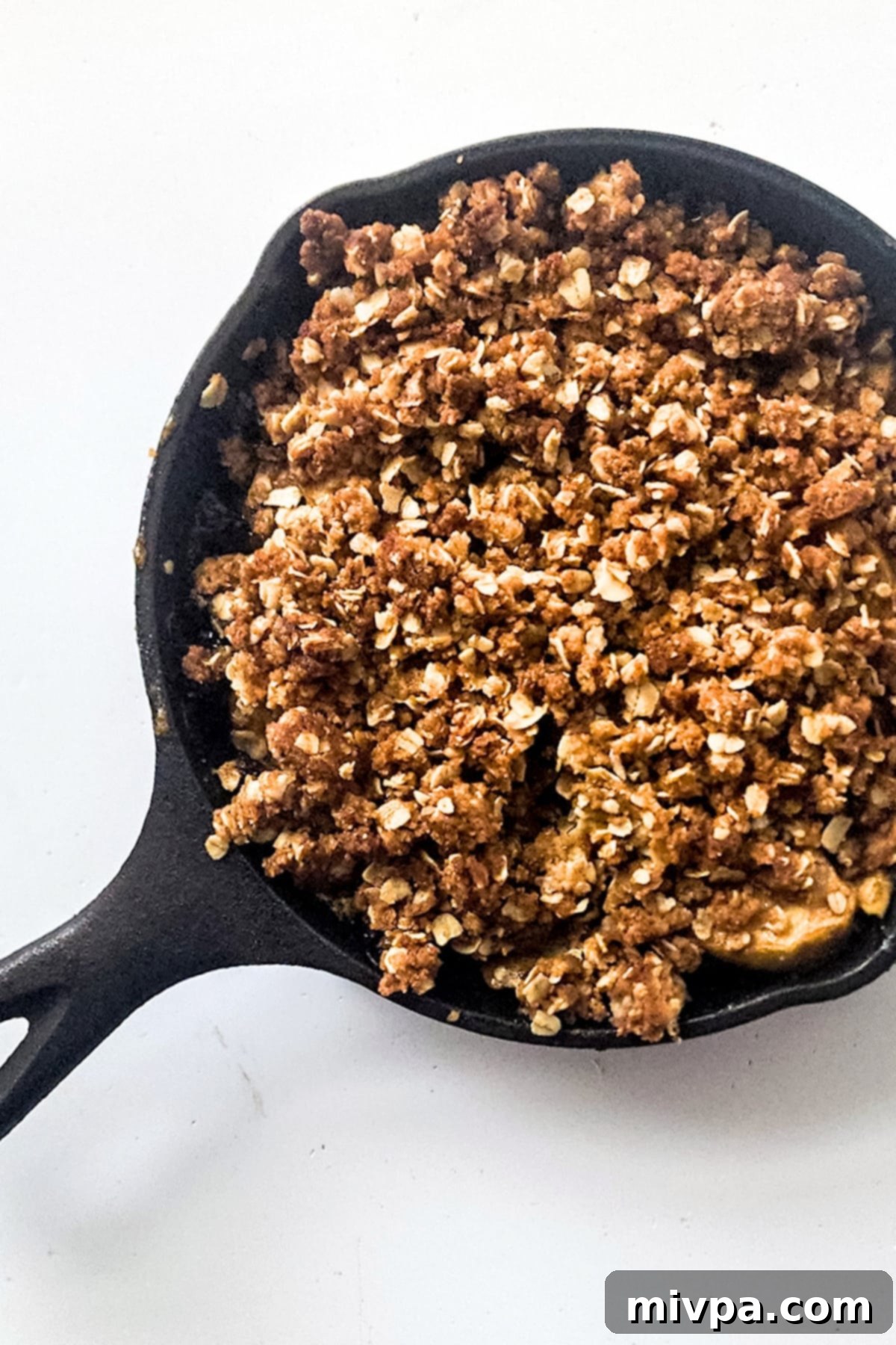 Freshly baked gluten-free apple crisp, golden and bubbling, in a cast iron skillet, just out of the oven.