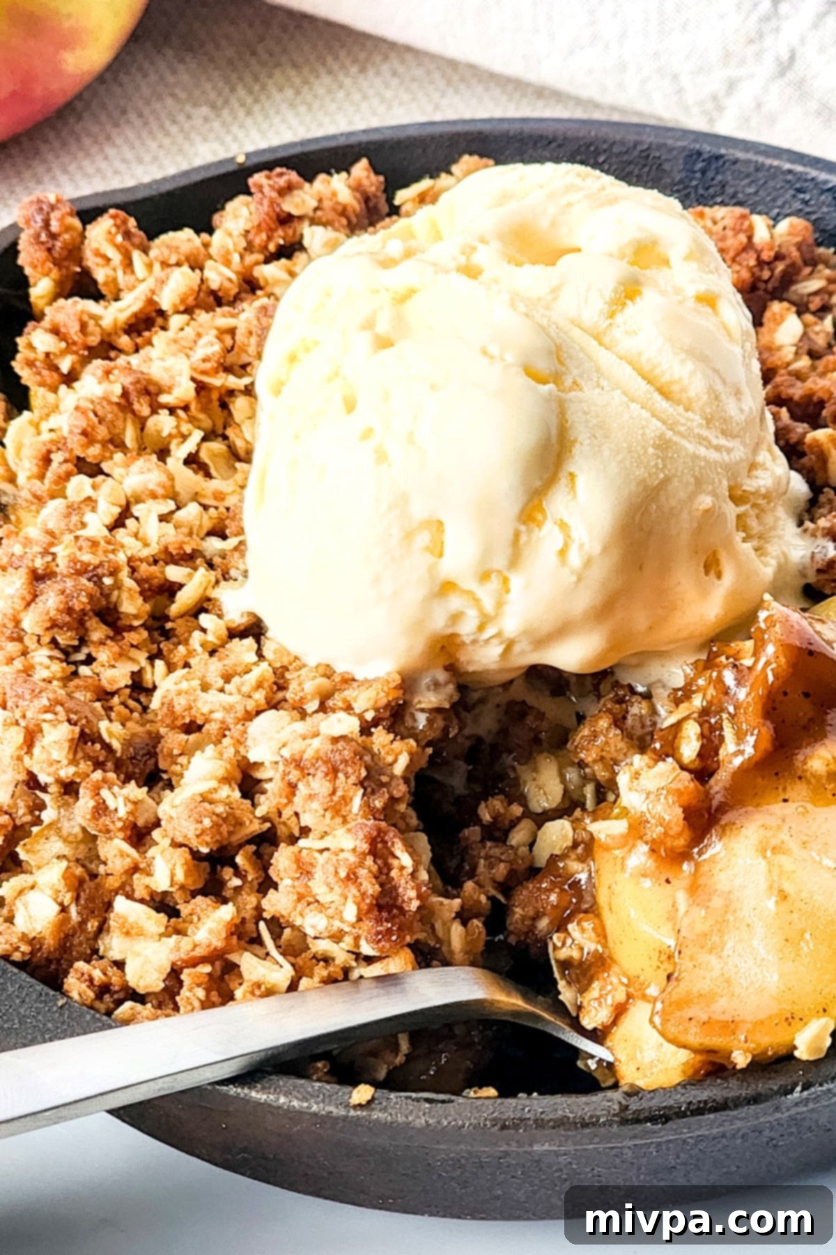 Scooping into a pan of gluten-free dairy-free apple crisp, showing the warm, gooey apple filling and crisp oat topping.