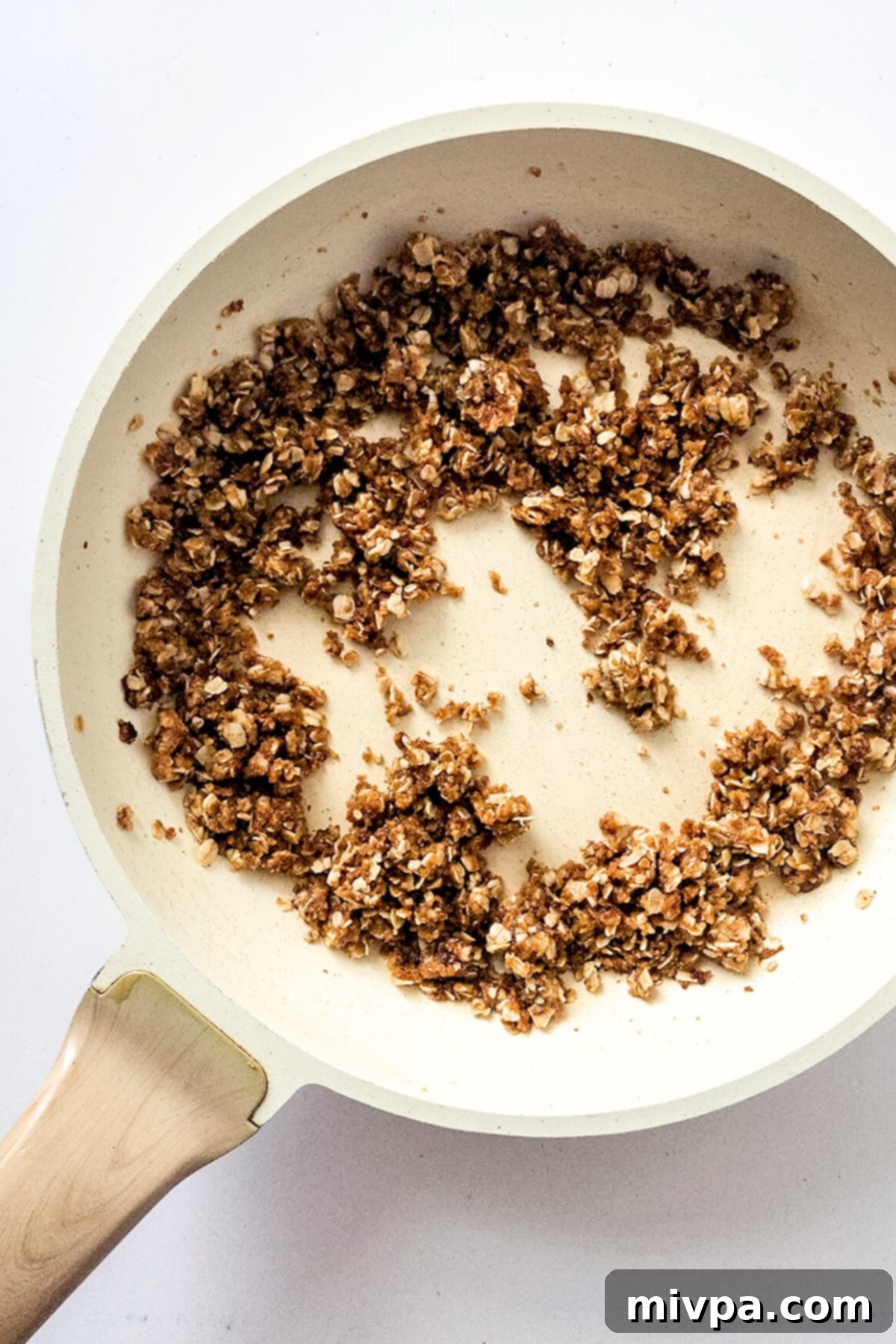 Golden brown oat mixture simmering gently in a pan, showcasing its crumbly texture.