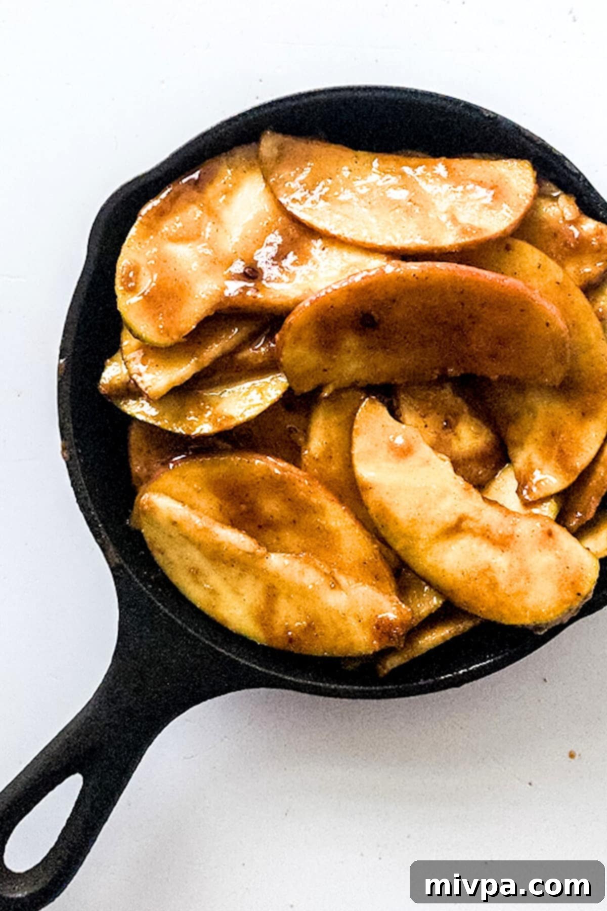Caramelized apple slices arranged neatly in a cast iron pan, ready for the topping.
