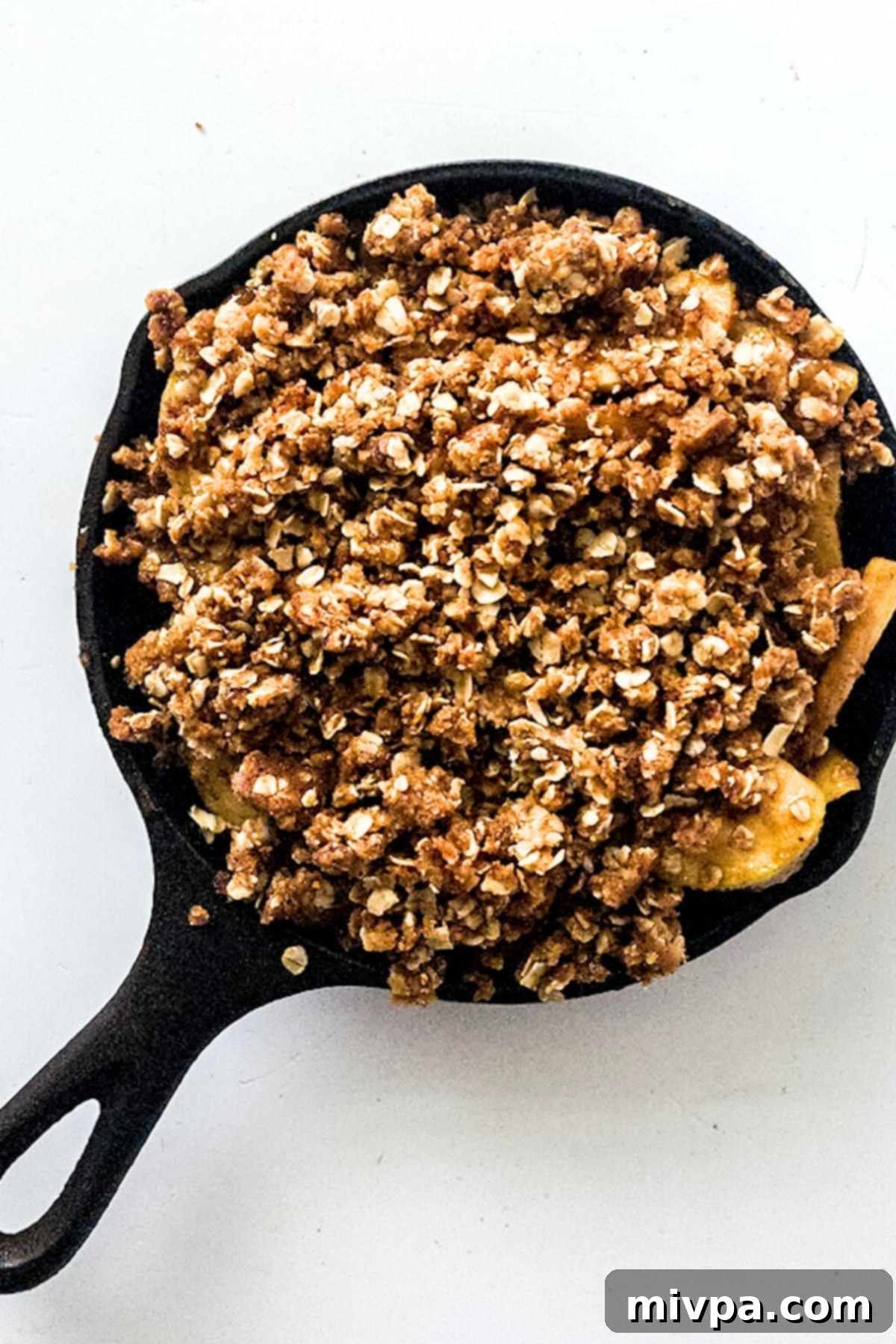 Gluten-free apple crisp in pan with oat topping, ready to be baked to perfection.