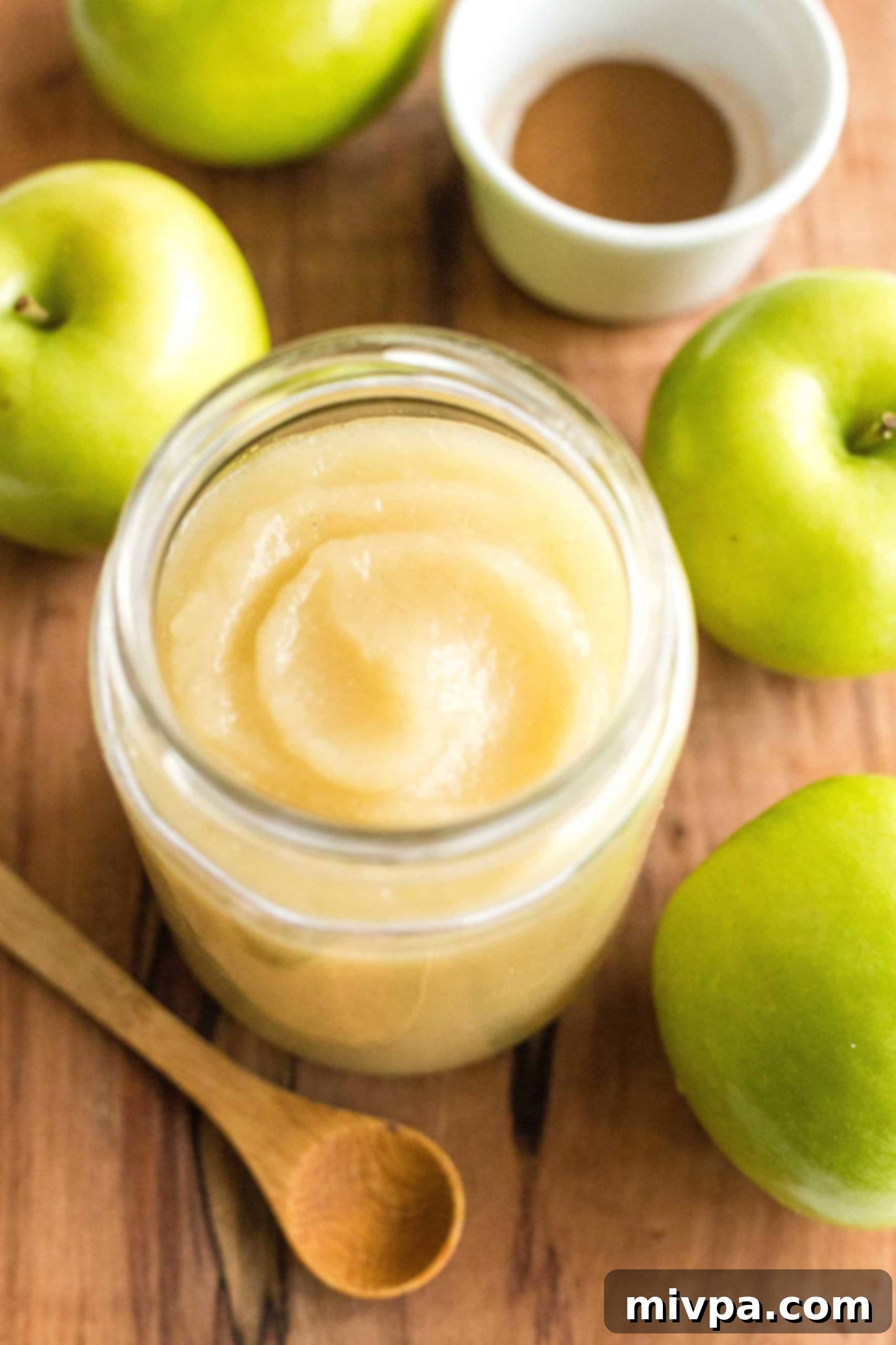 A jar of homemade applesauce on wooden board.