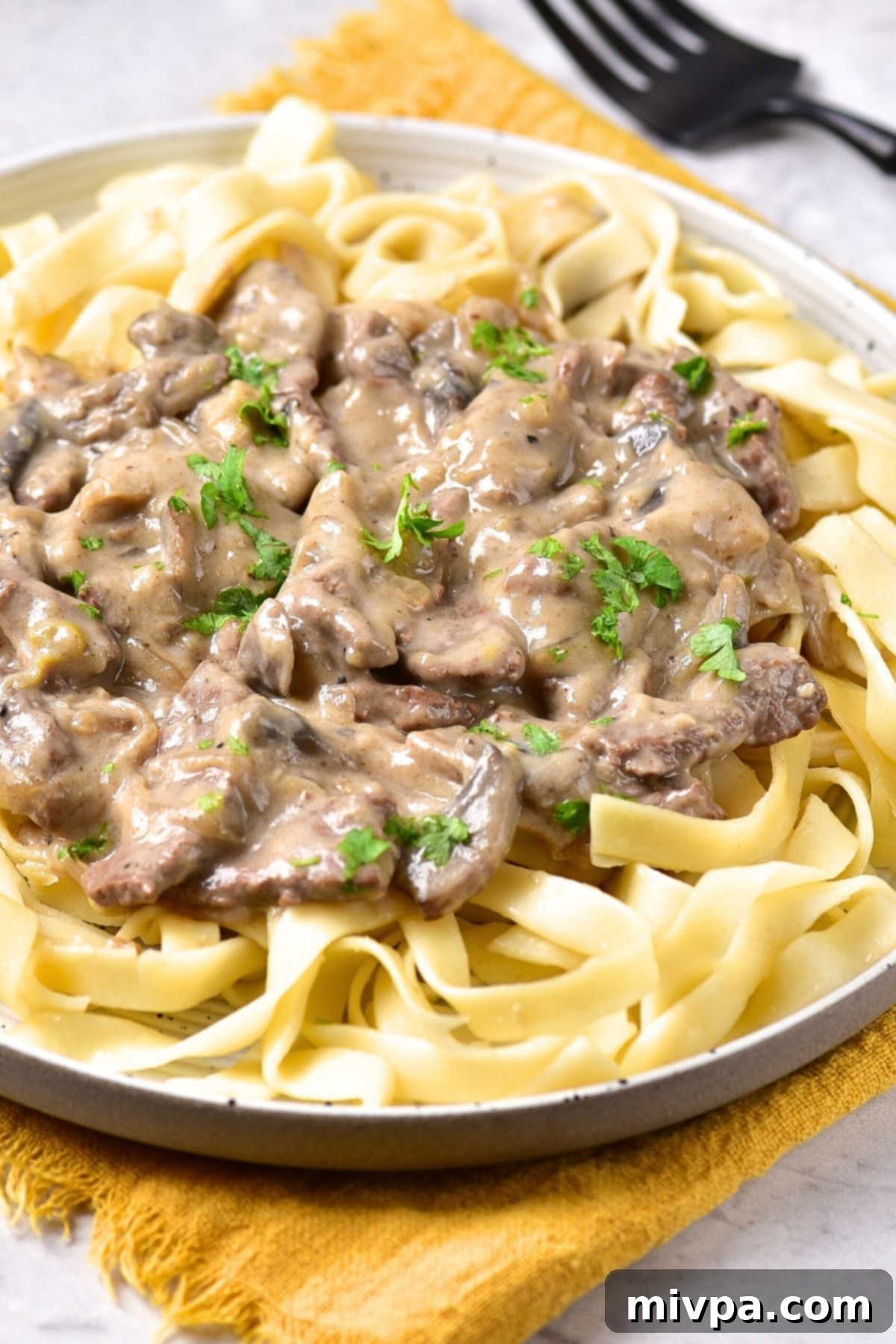 Gluten-Free Beef Stroganoff (Dairy-Free) Up close shot of gluten-free beef stroganoff over fettuccine noodles.