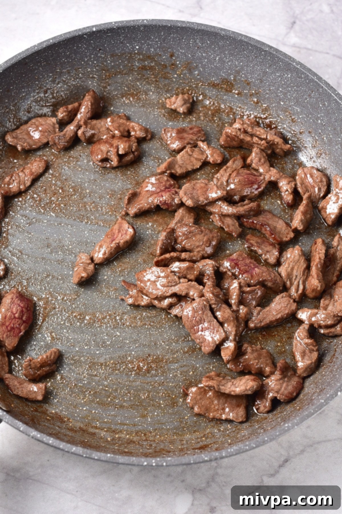 Gluten-Free Dairy-Free Beef Stroganoff Sautéed beef slices in large pan.
