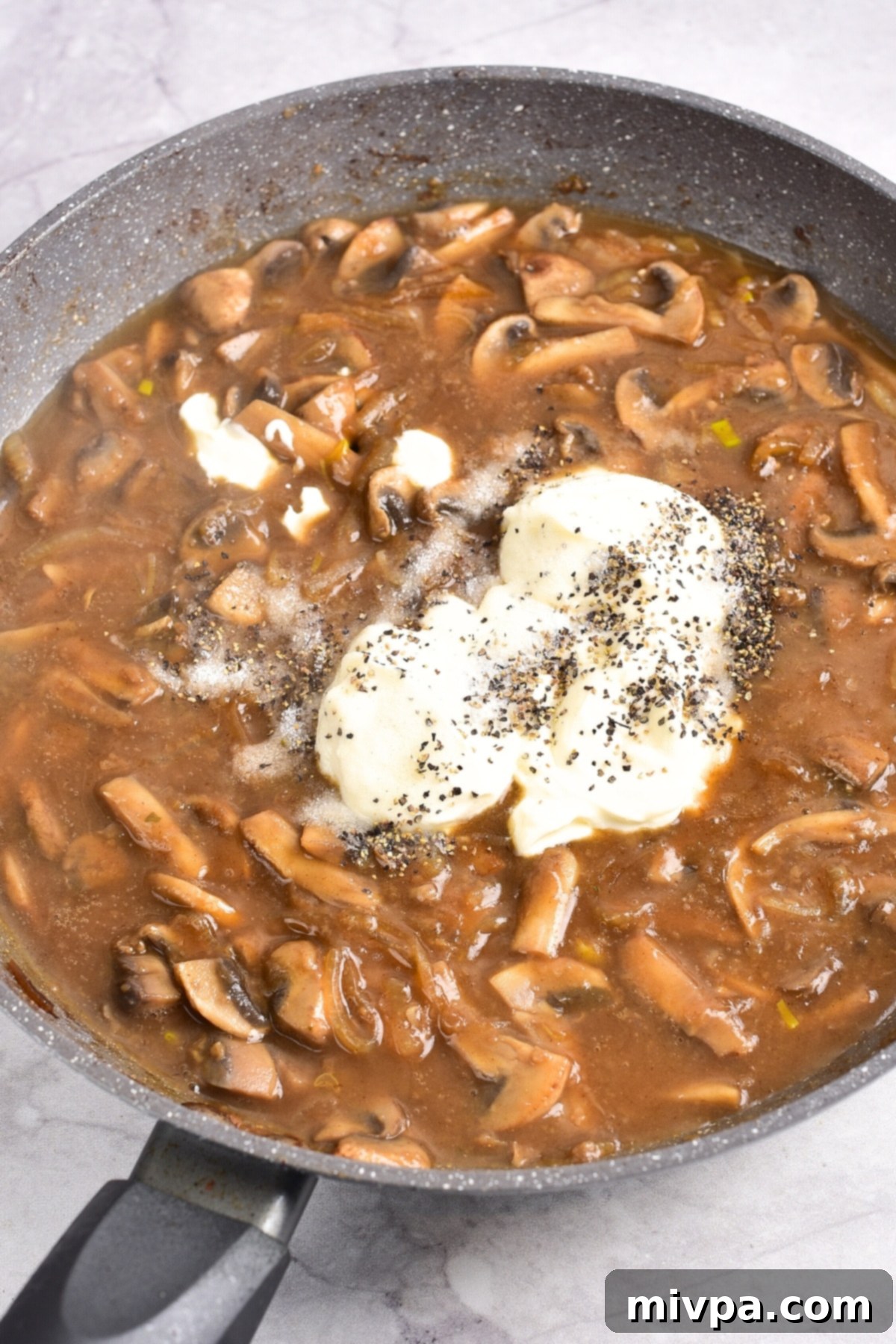 Gluten-Free Beef Stroganoff Recipe (Dairy-Free) Sour cream and black pepper on top of mushroom sauce.