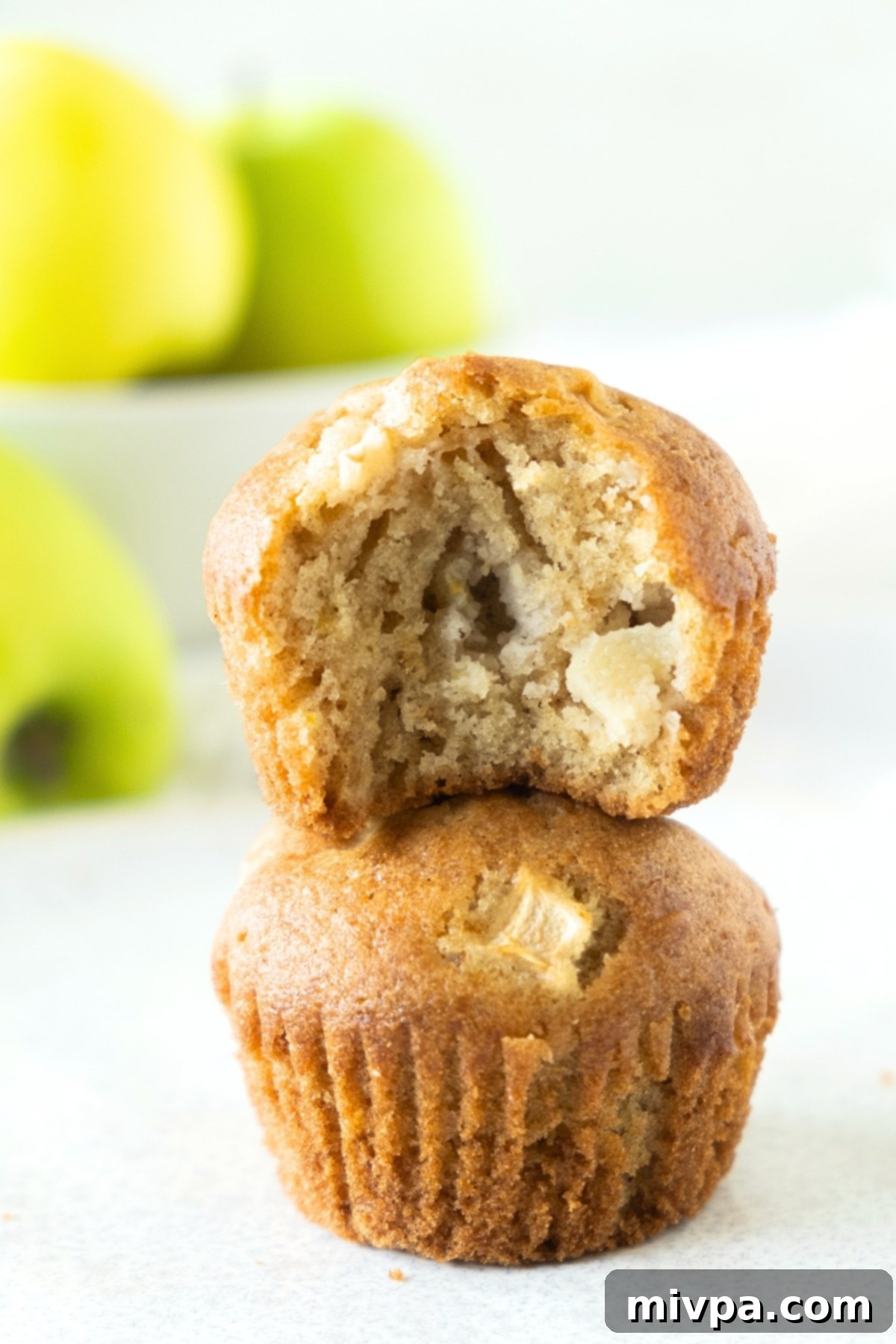 A close-up of beautifully baked, half-eaten apple muffins, showcasing their rich texture and golden crust.