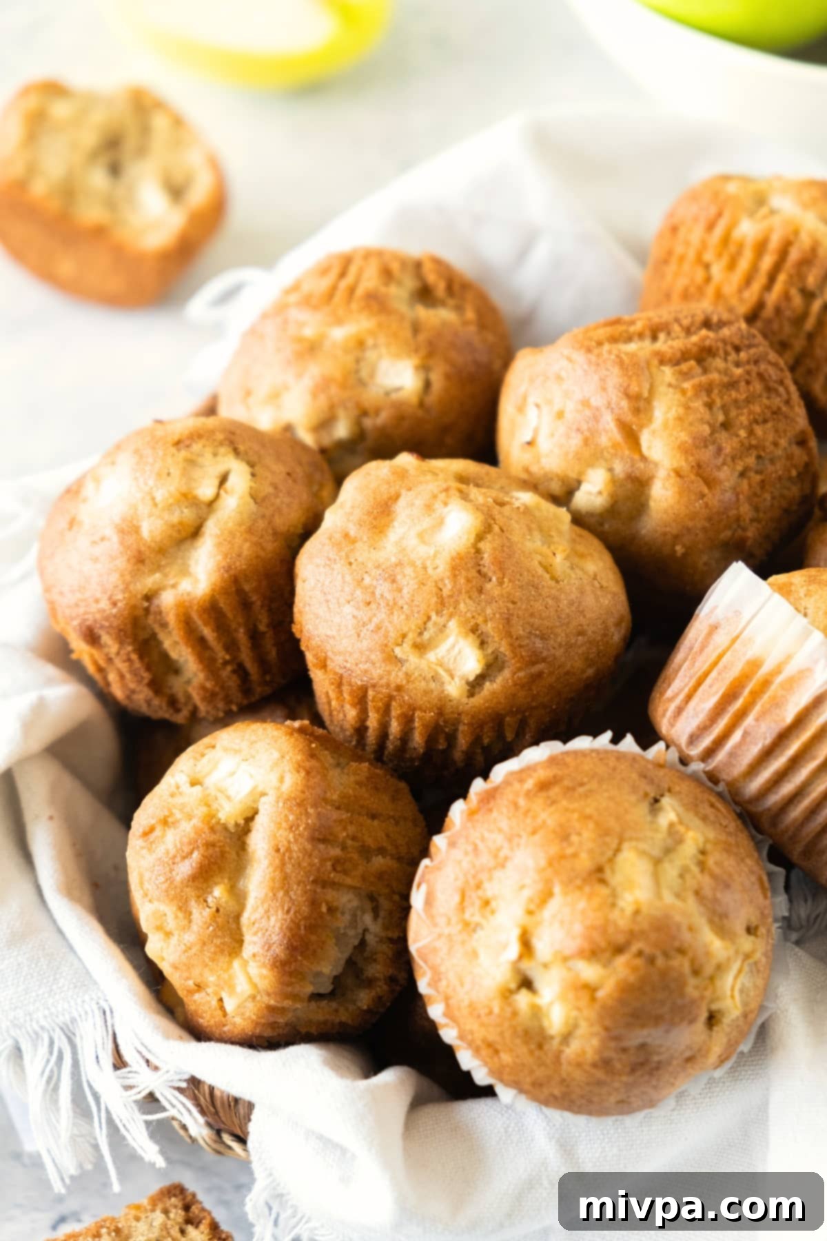 A large basket brimming with golden gluten-free apple cinnamon muffins, ready for sharing.