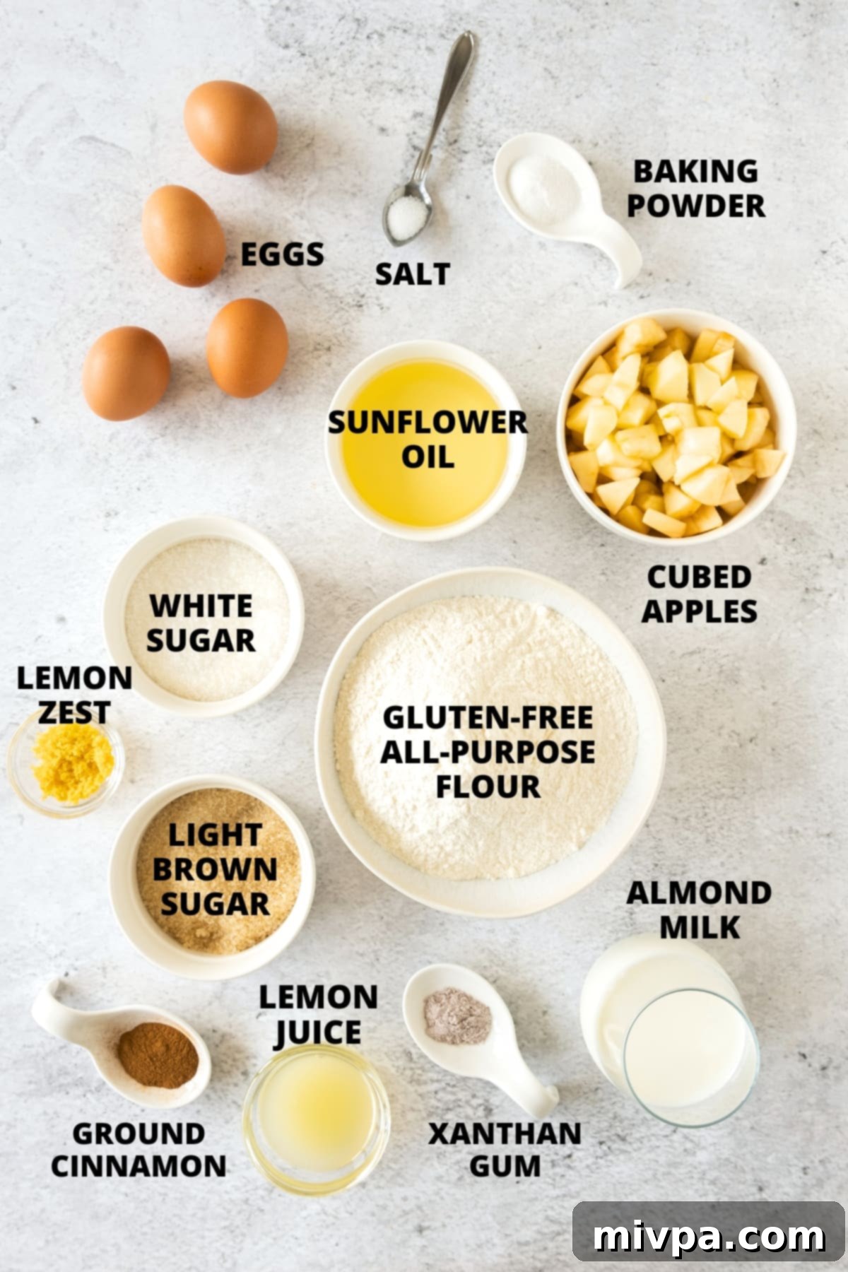 All the ingredients for the gluten-free apple muffin recipe meticulously laid out on a clean white board.