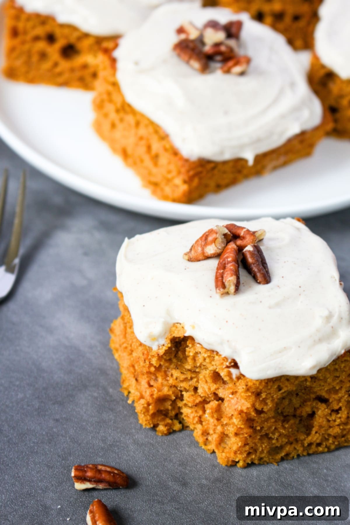 Half-eaten square of gluten-free pumpkin cake with creamy cinnamon cream cheese frosting.